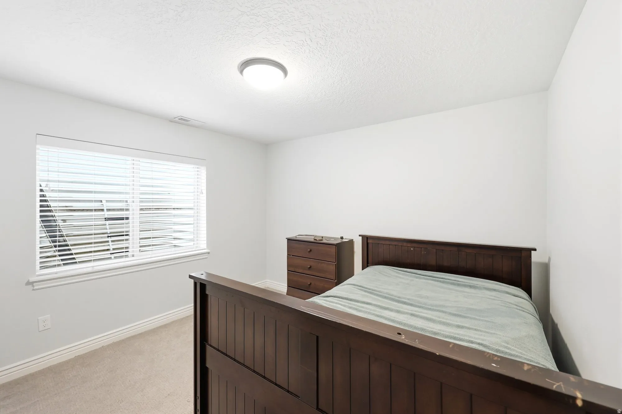 Bedroom with light colored carpet and a textured ceiling