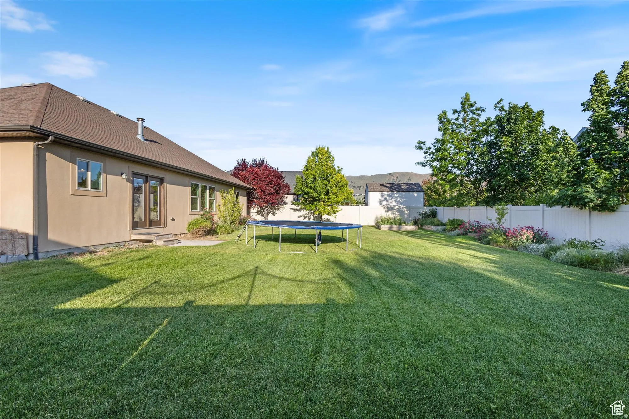 Fenced backyard with a trampoline and a patio area