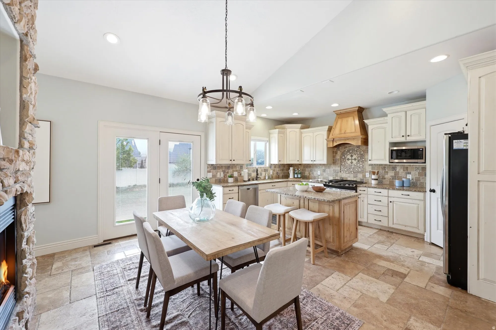Dining space with stone tile flooring, lofted ceiling, suspended lighting, and a fireplace