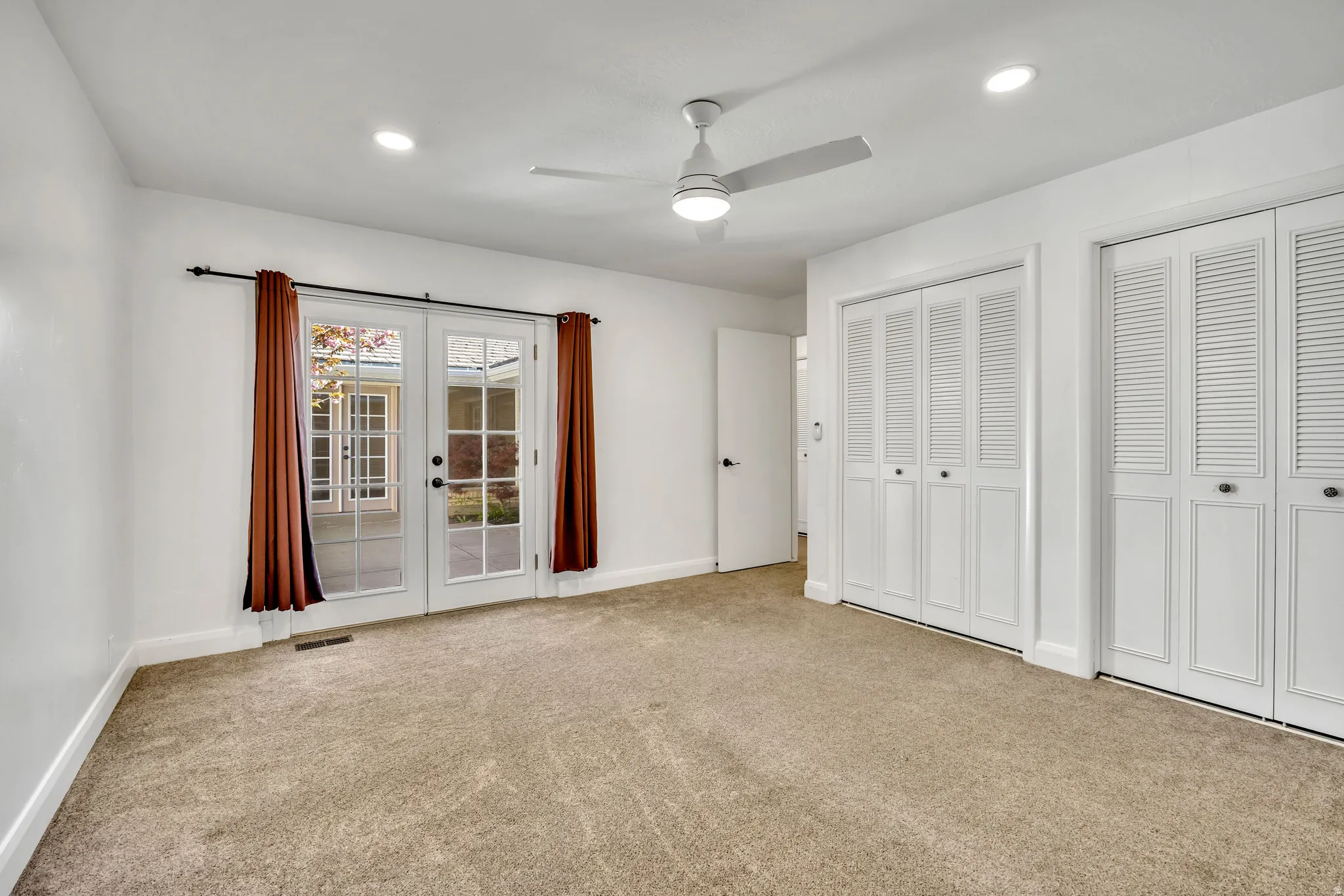 Unfurnished bedroom featuring french doors, two closets, light carpet, ceiling fan, and recessed lighting