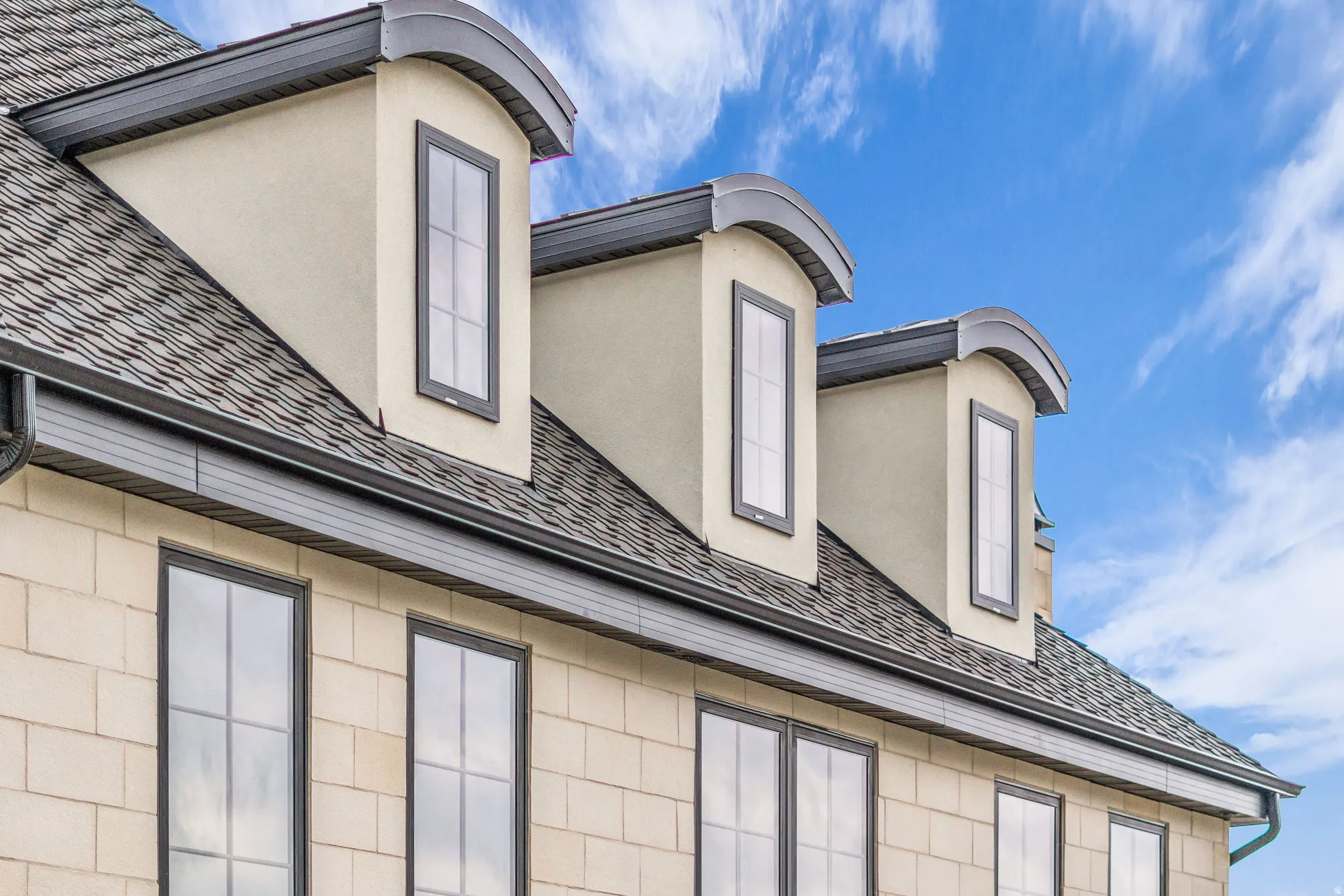 Exterior view of gutters, stucco siding, and a downspout