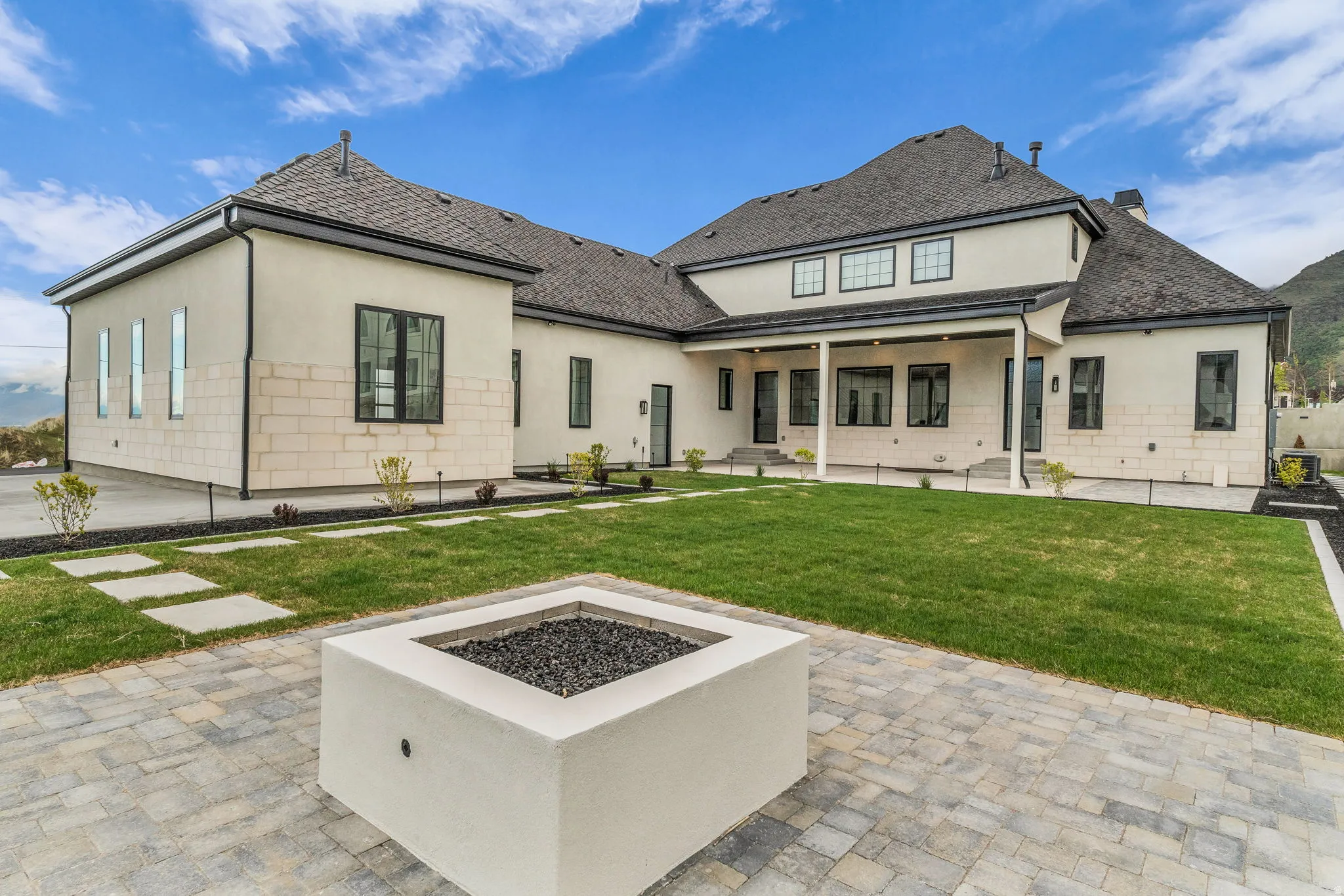 Rear view of property with a patio, a fire pit, stucco siding, a lawn, and roof with shingles