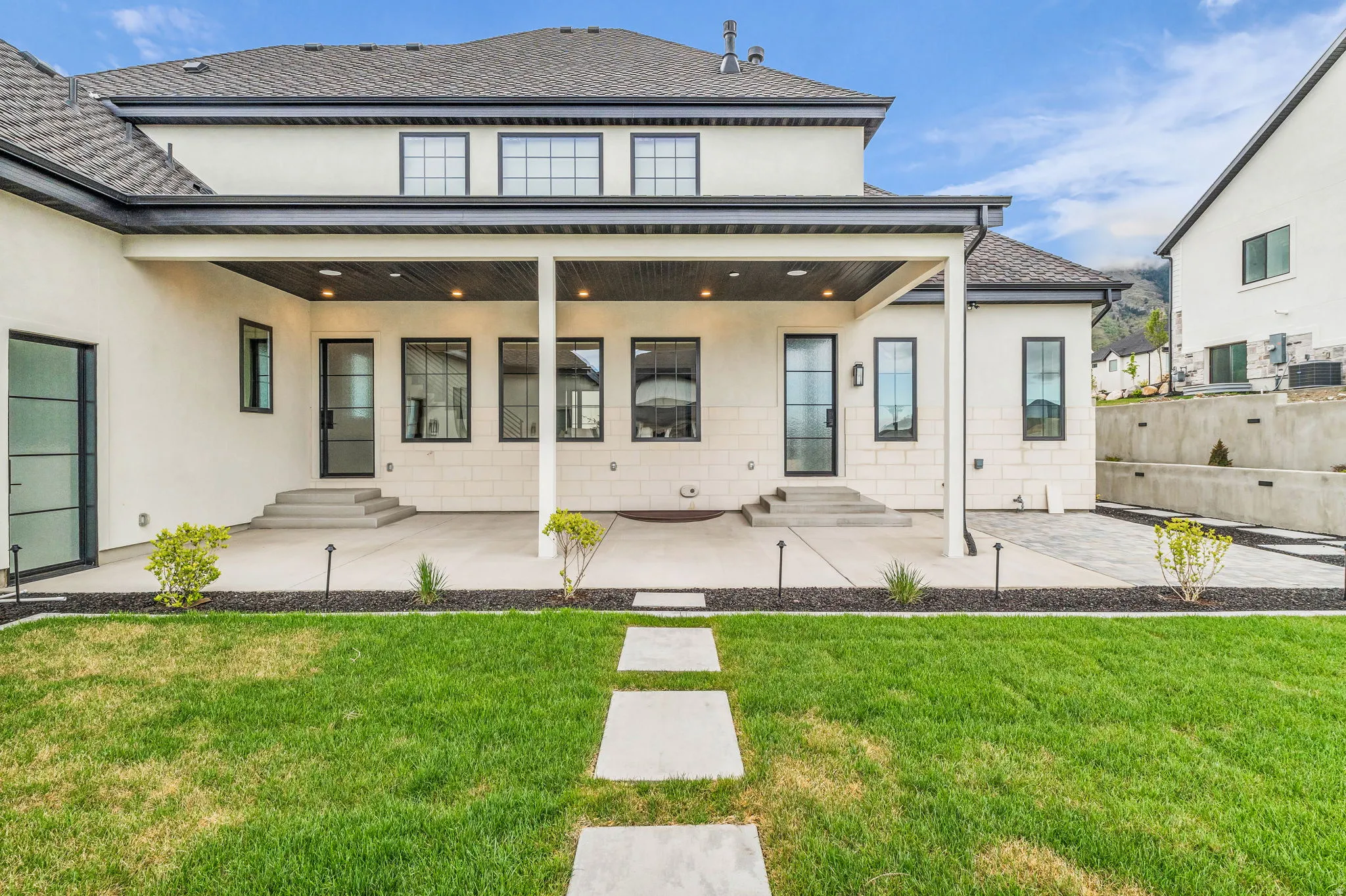Back of house featuring a patio, a yard, stucco siding, and entry steps