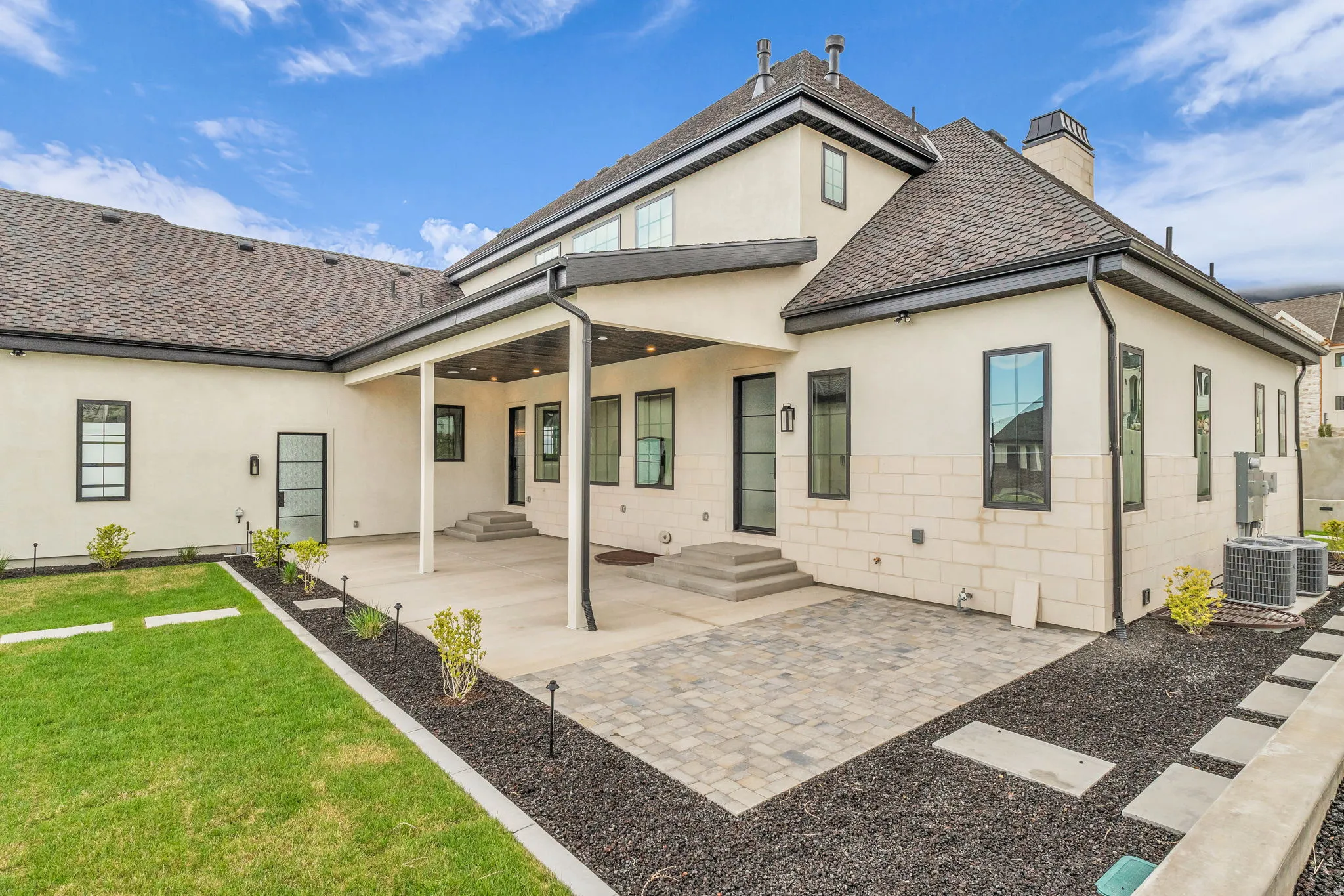 Back of property with a patio area, roof with shingles, stucco siding, and a yard