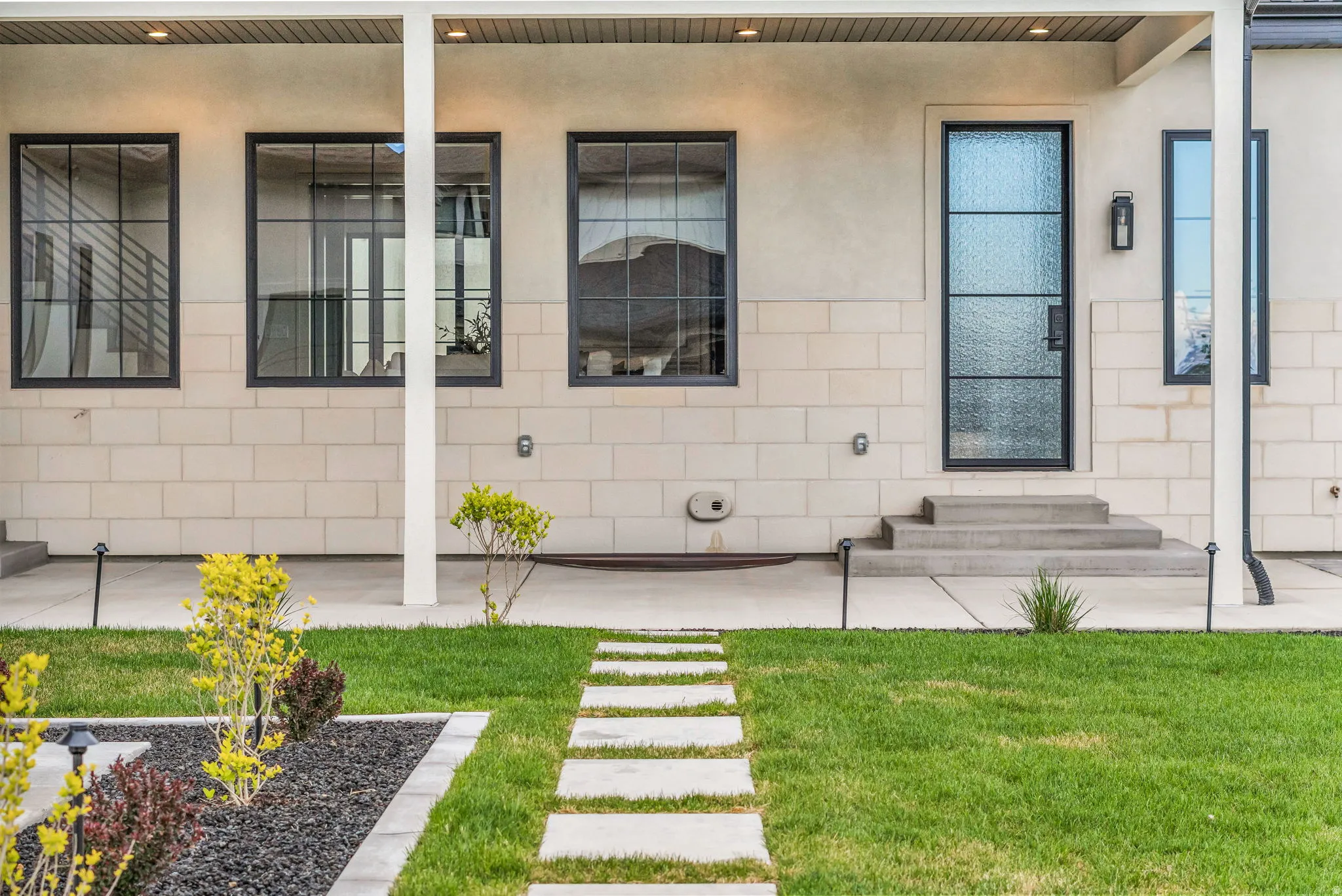 View of exterior entry featuring a yard, stucco siding, concrete block siding, and a porch