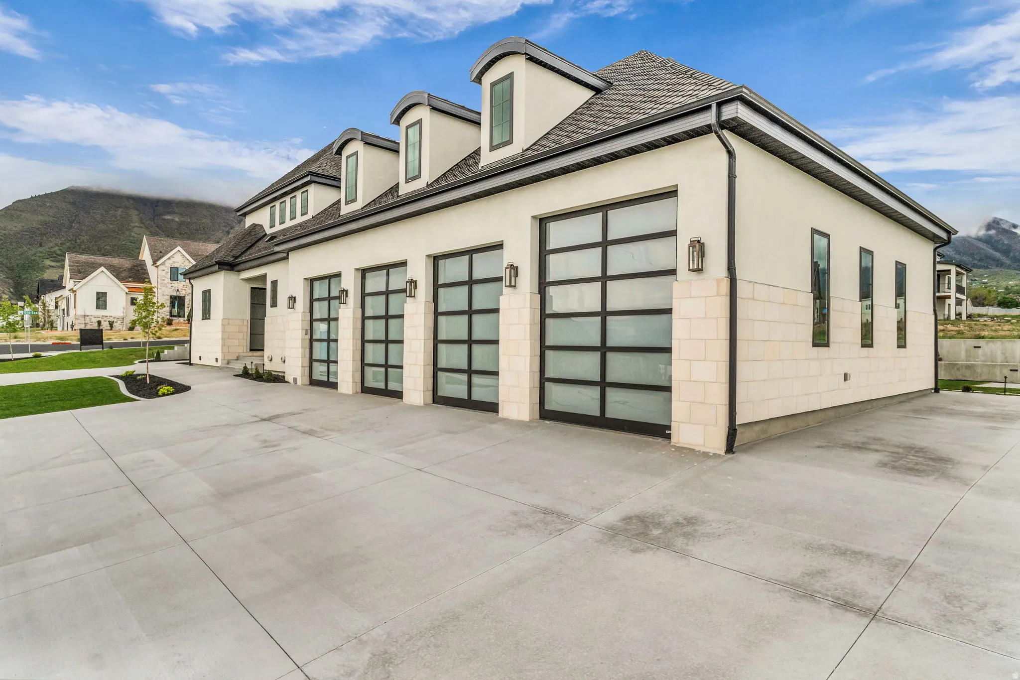 View of side of property with a mountain view, stucco siding, concrete driveway, and an attached garage