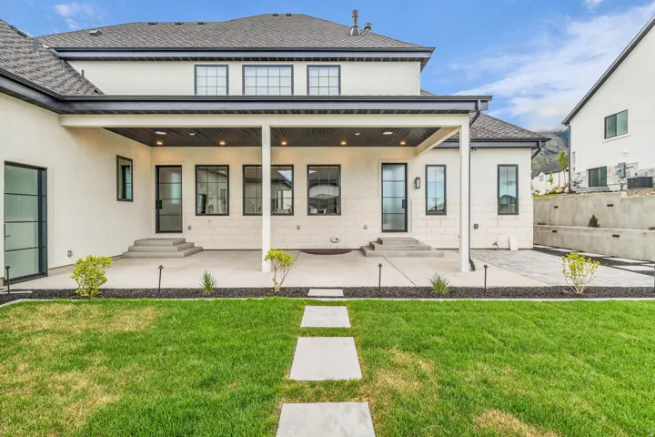Back of house featuring a patio, a yard, stucco siding, and entry steps