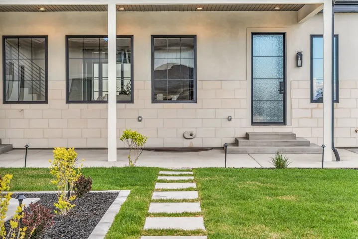 View of exterior entry featuring a yard, stucco siding, concrete block siding, and a porch