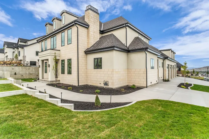 View of side of property with a lawn, stucco siding, concrete driveway, and a chimney