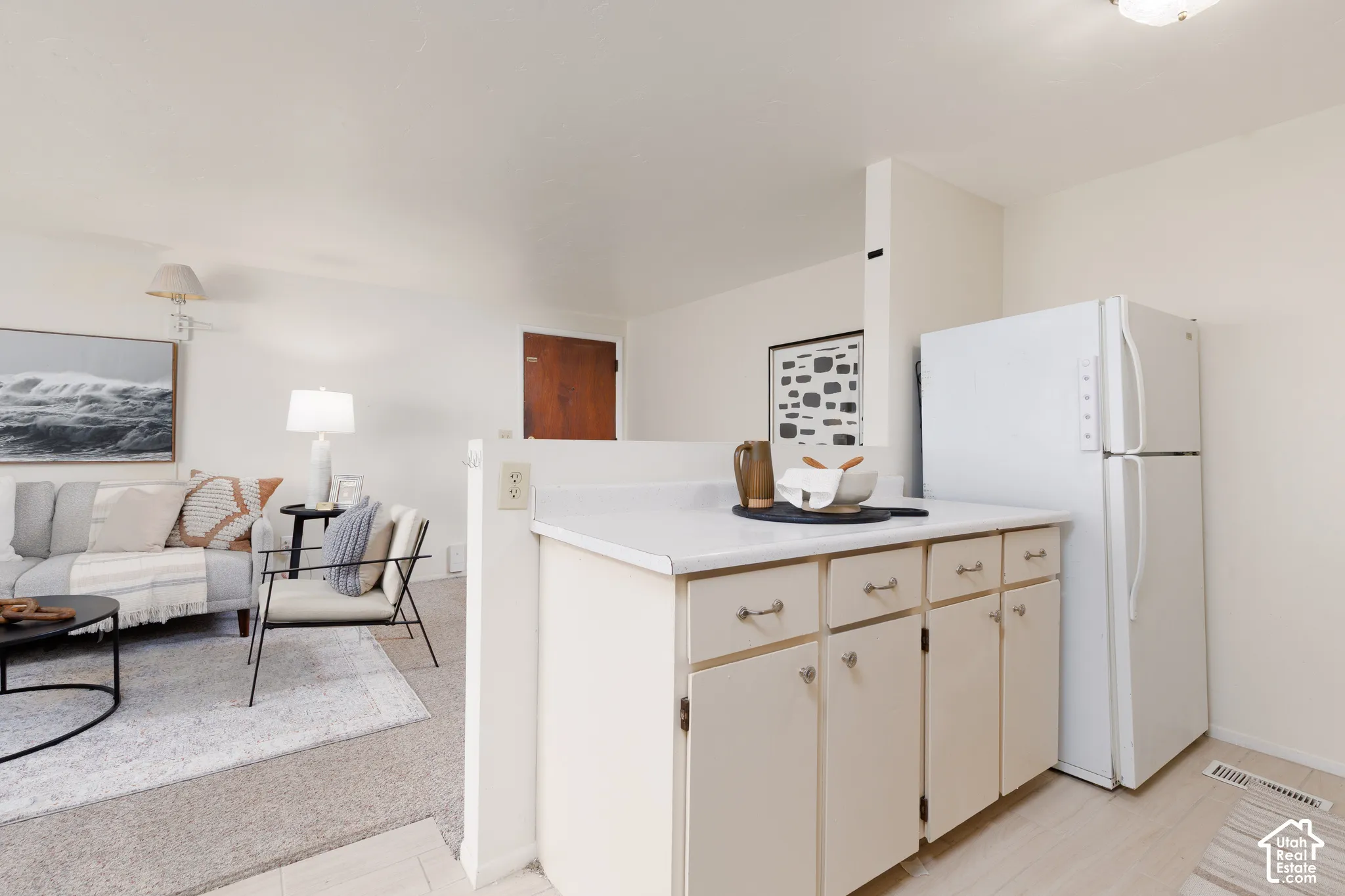 Kitchenette featuring cream cabinetry with silver hardware, white countertop, and white refrigerator
