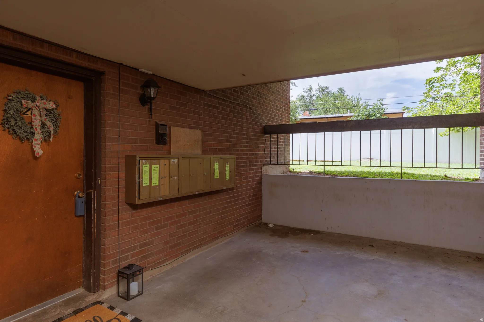 Covered entryway featuring a red brick wall, a solid entry door, built-in mailboxes, and a concrete patio