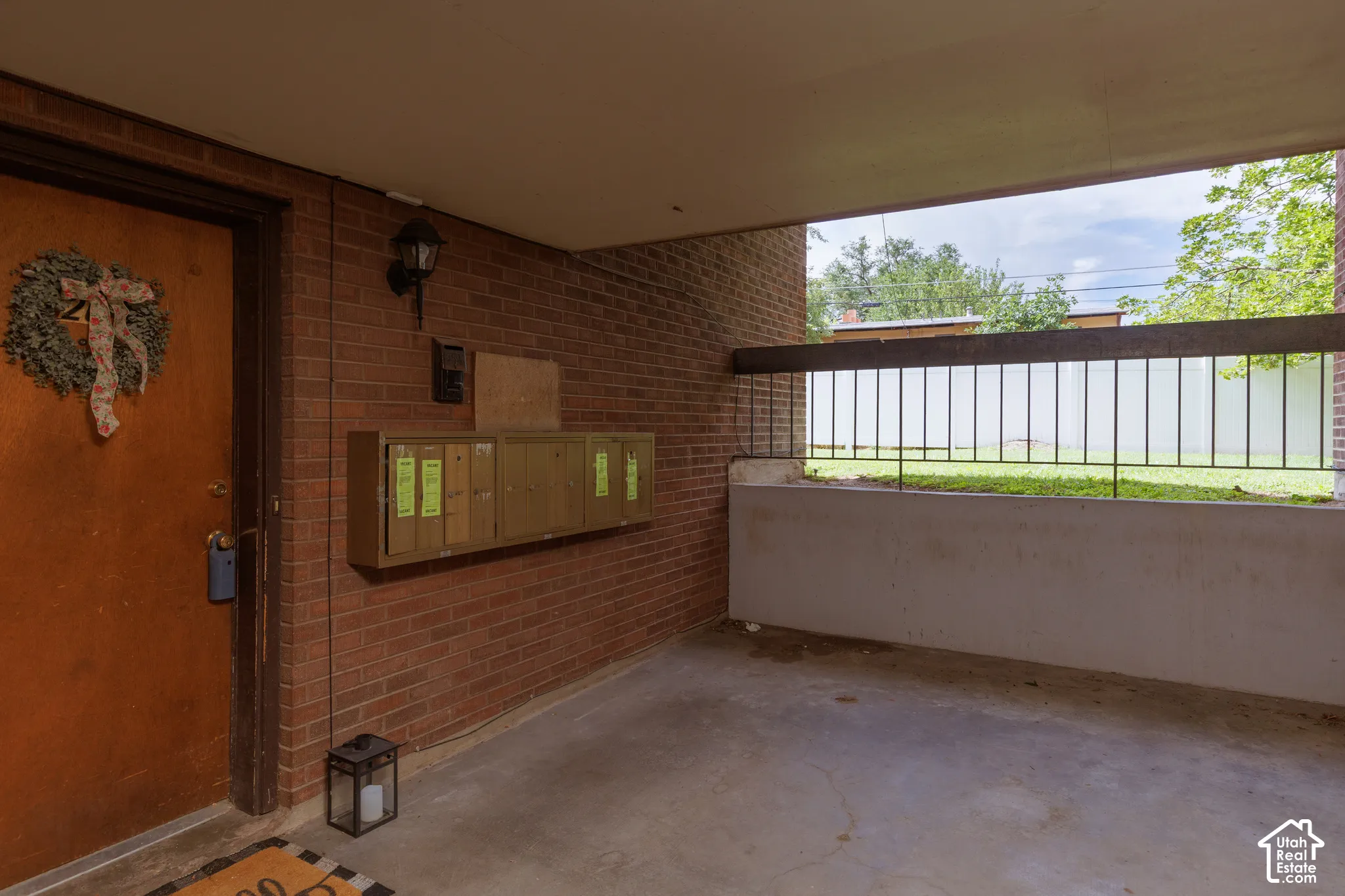 Covered entryway featuring a red brick wall, a solid entry door, built-in mailboxes, and a concrete patio
