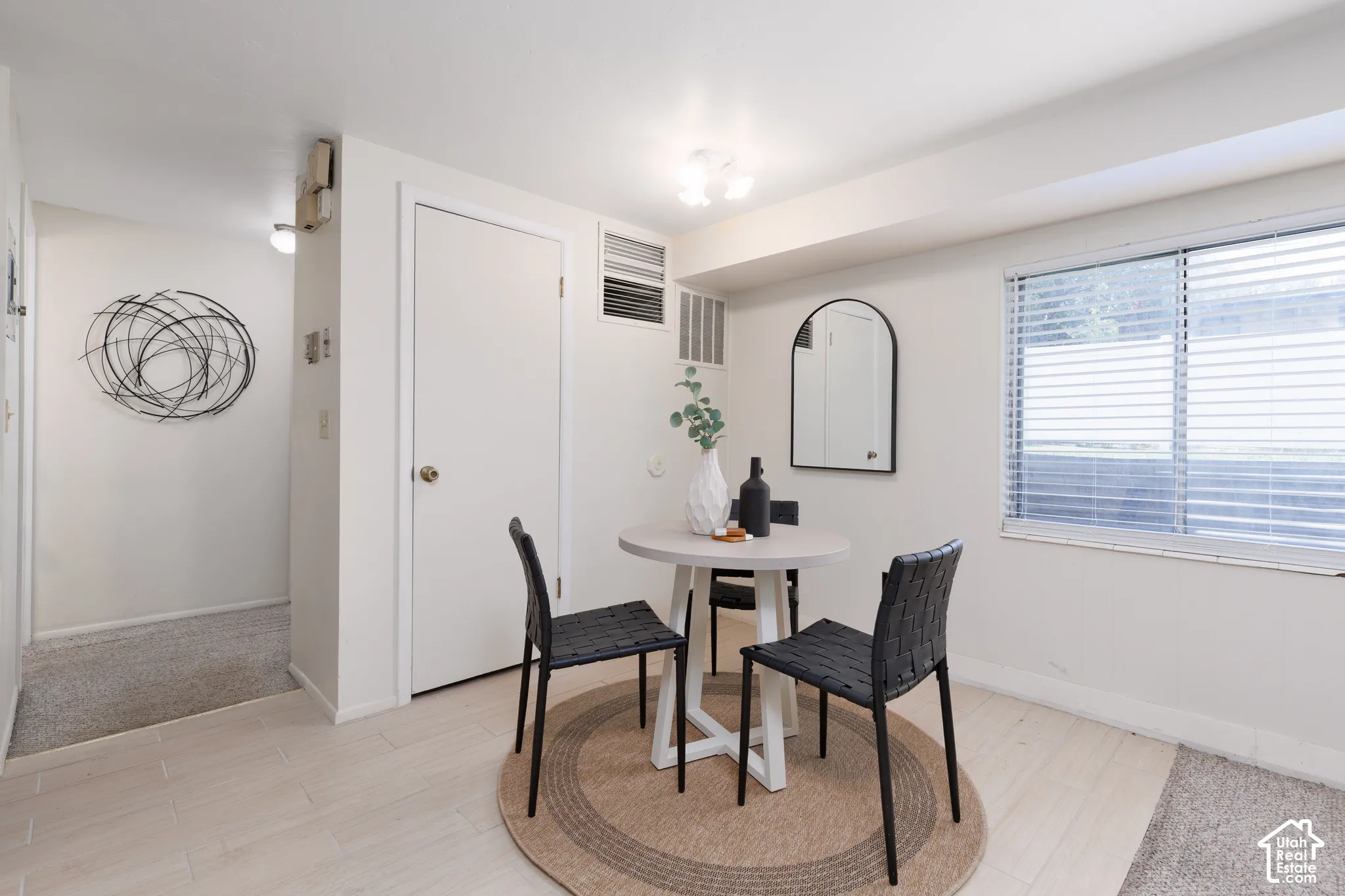 Open living area featuring wood-finish flooring, a bright window with blinds, and a white interior door