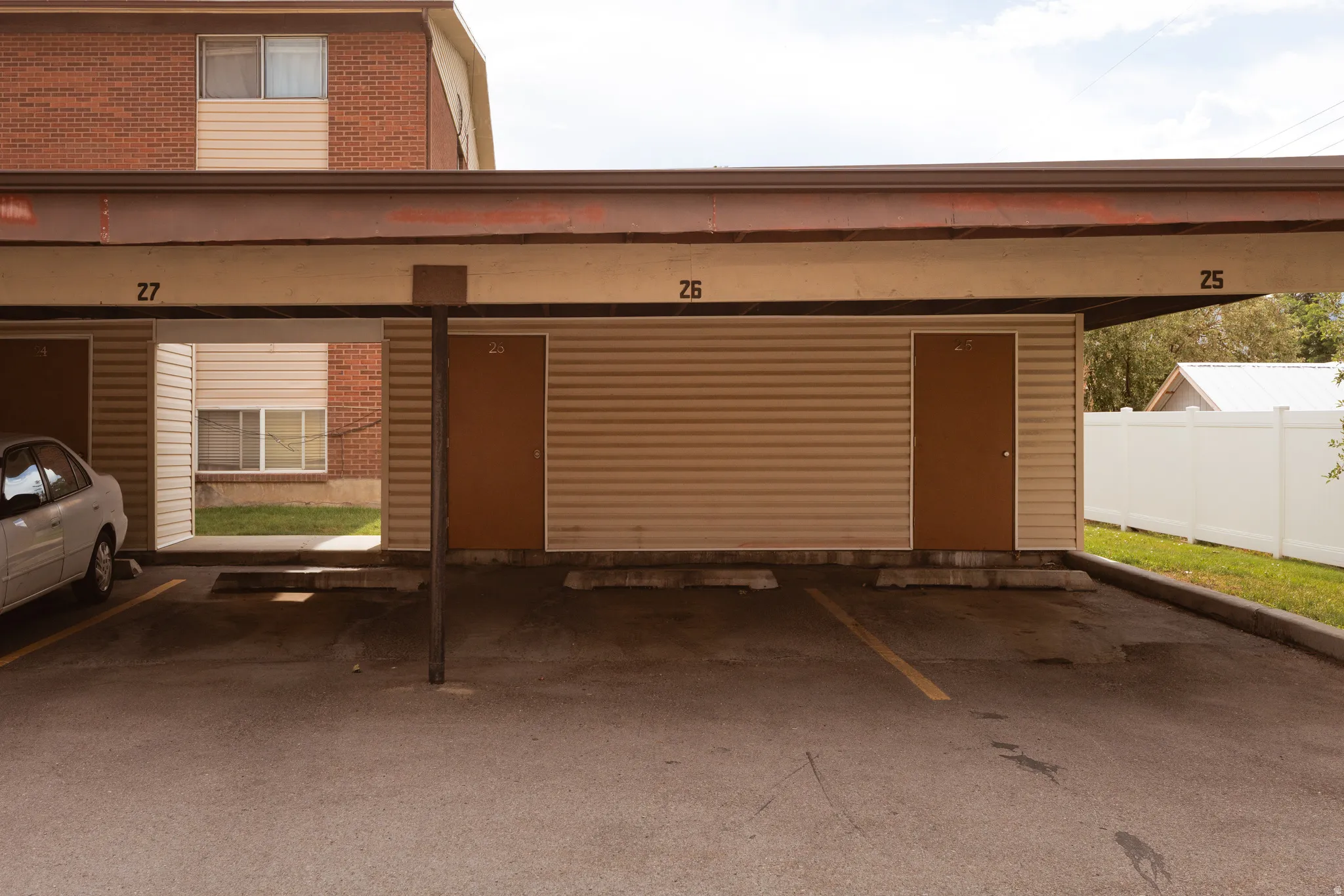 Covered parking structure featuring designated parking spaces and outdoor storage