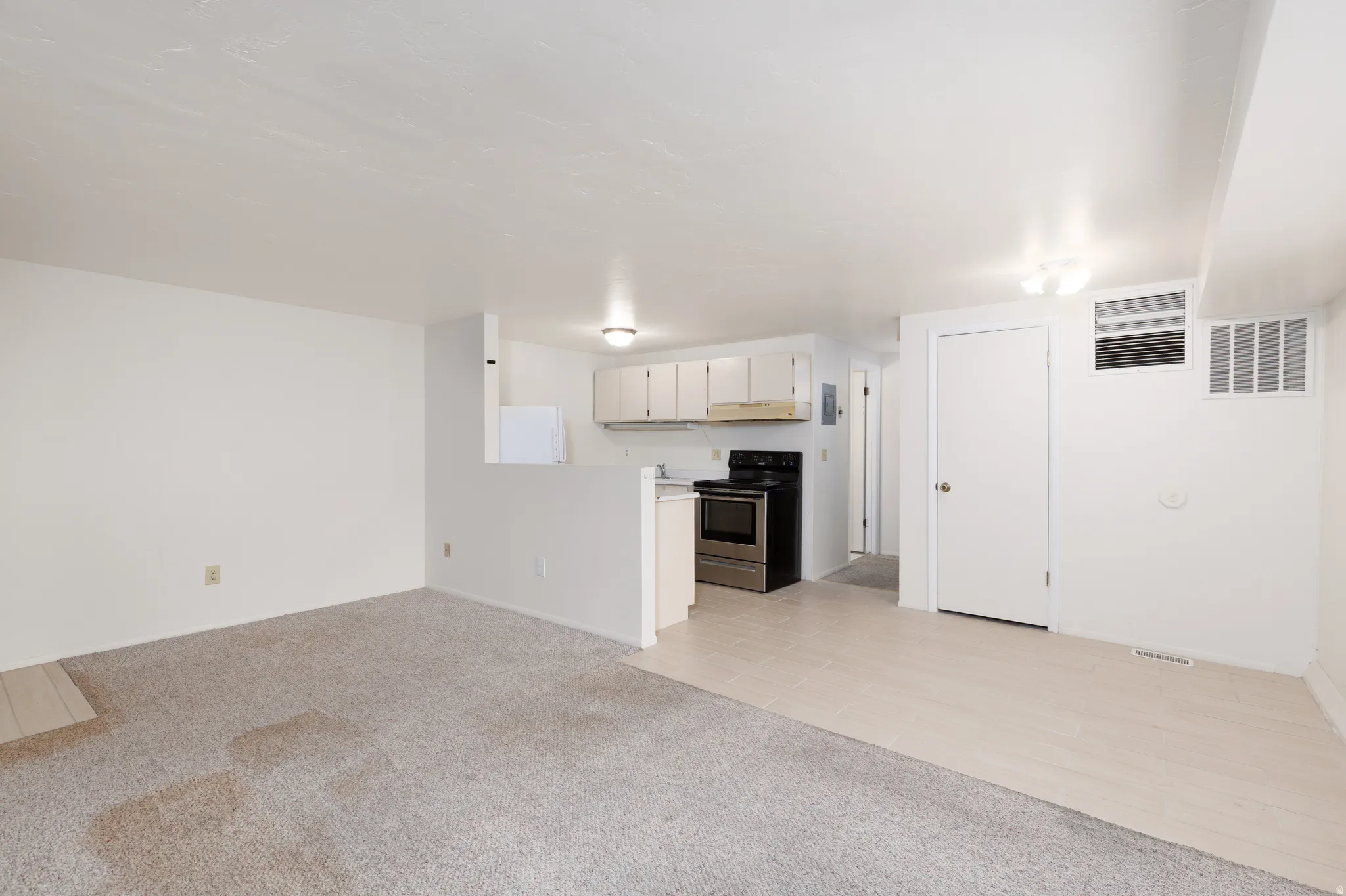 Unfurnished living room featuring light carpet and light tile patterned flooring