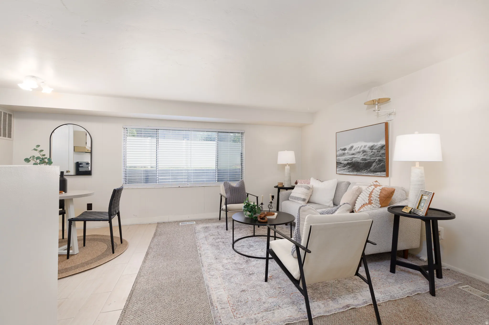 Open concept living area with light-toned wood-finish flooring, a rectangular window with blinds, and recessed lighting