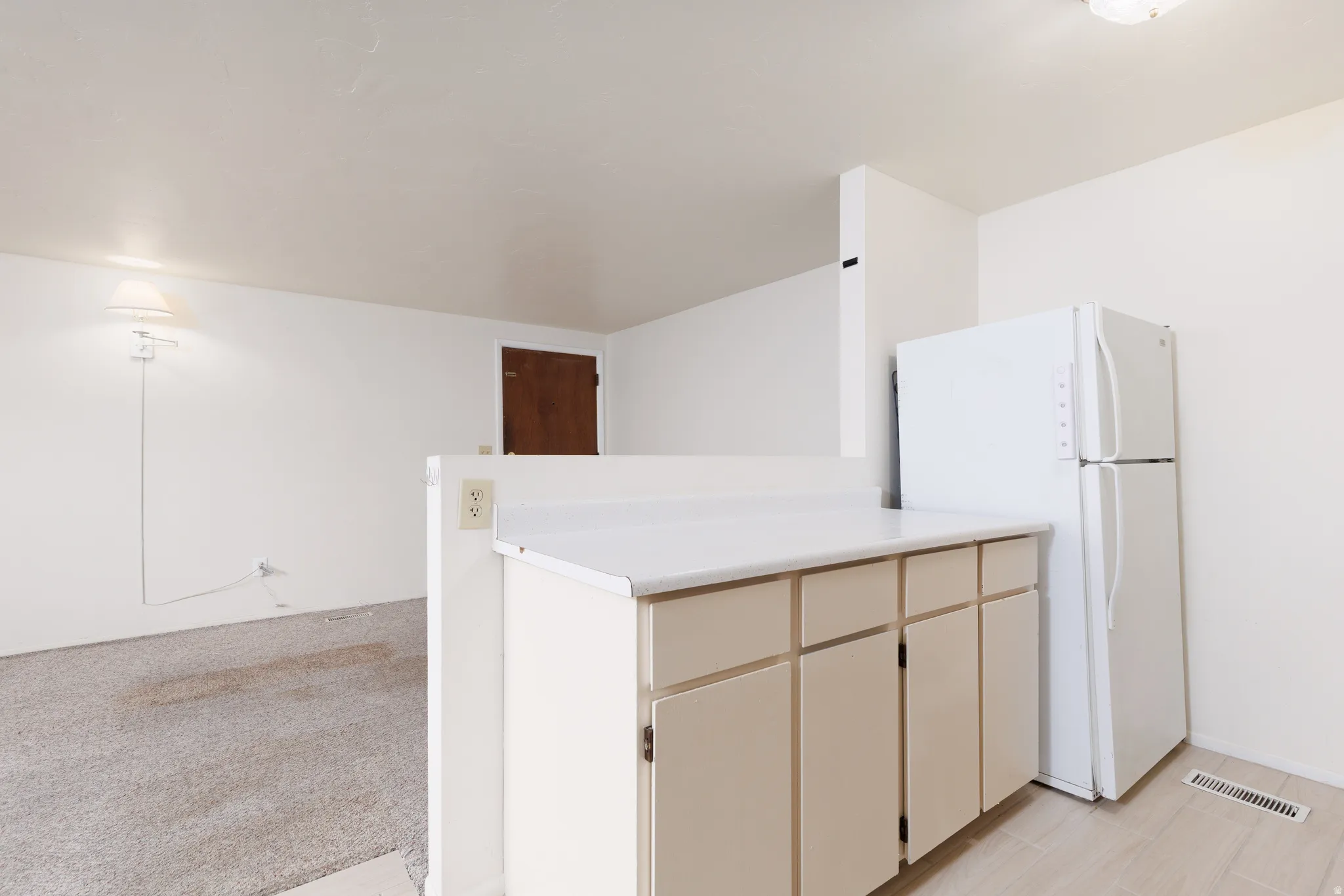 Kitchen with freestanding refrigerator, light countertops, a peninsula, and cream cabinets