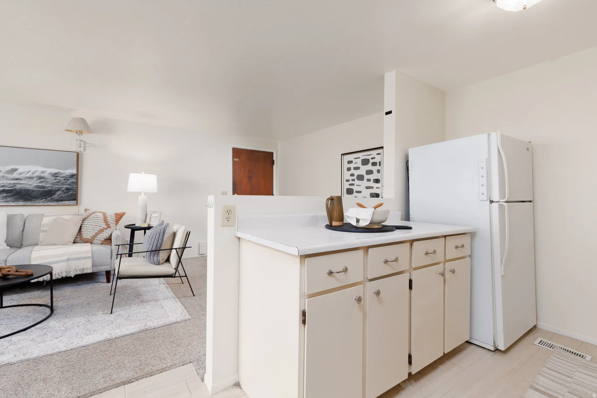 Kitchenette featuring cream cabinetry with silver hardware, white countertop, and white refrigerator