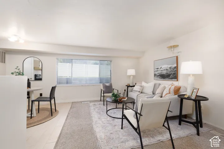 Open concept living area with light-toned wood-finish flooring, a rectangular window with blinds, and recessed lighting