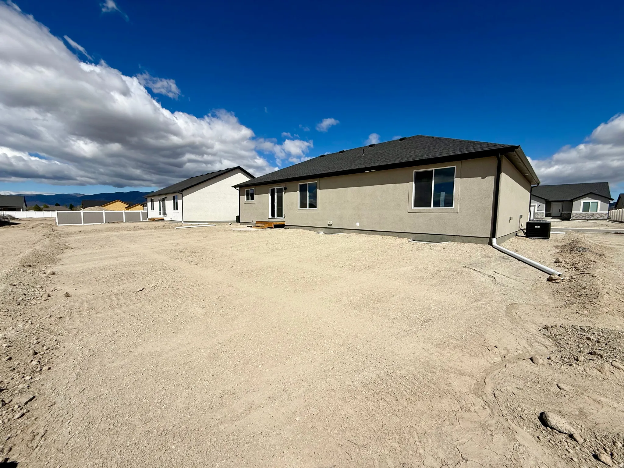 Back of house with stucco siding and roof with shingles