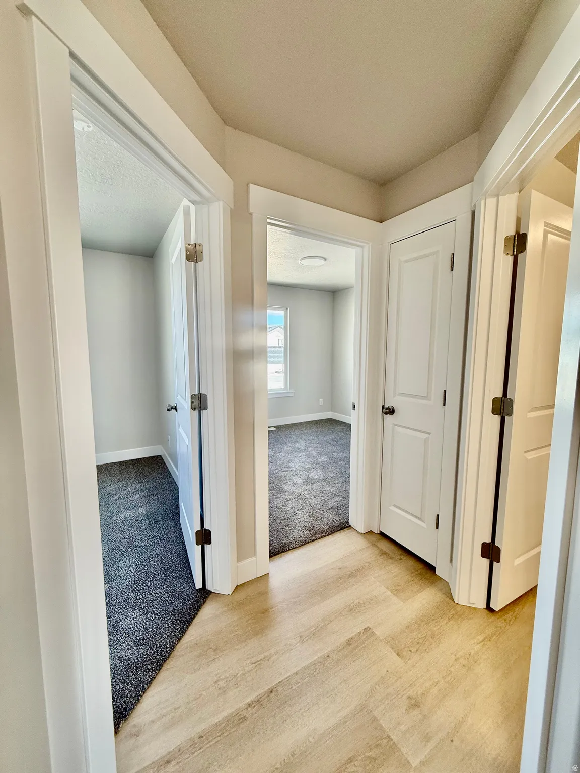 Corridor featuring light colored carpet and light wood-style floors