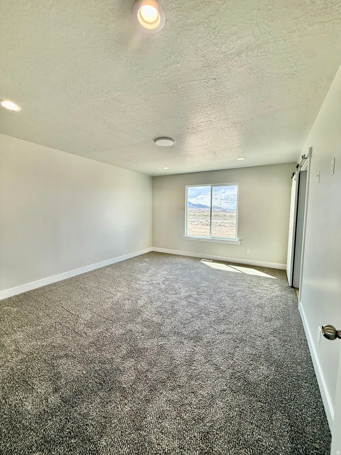 Carpeted empty room with baseboards and a textured ceiling