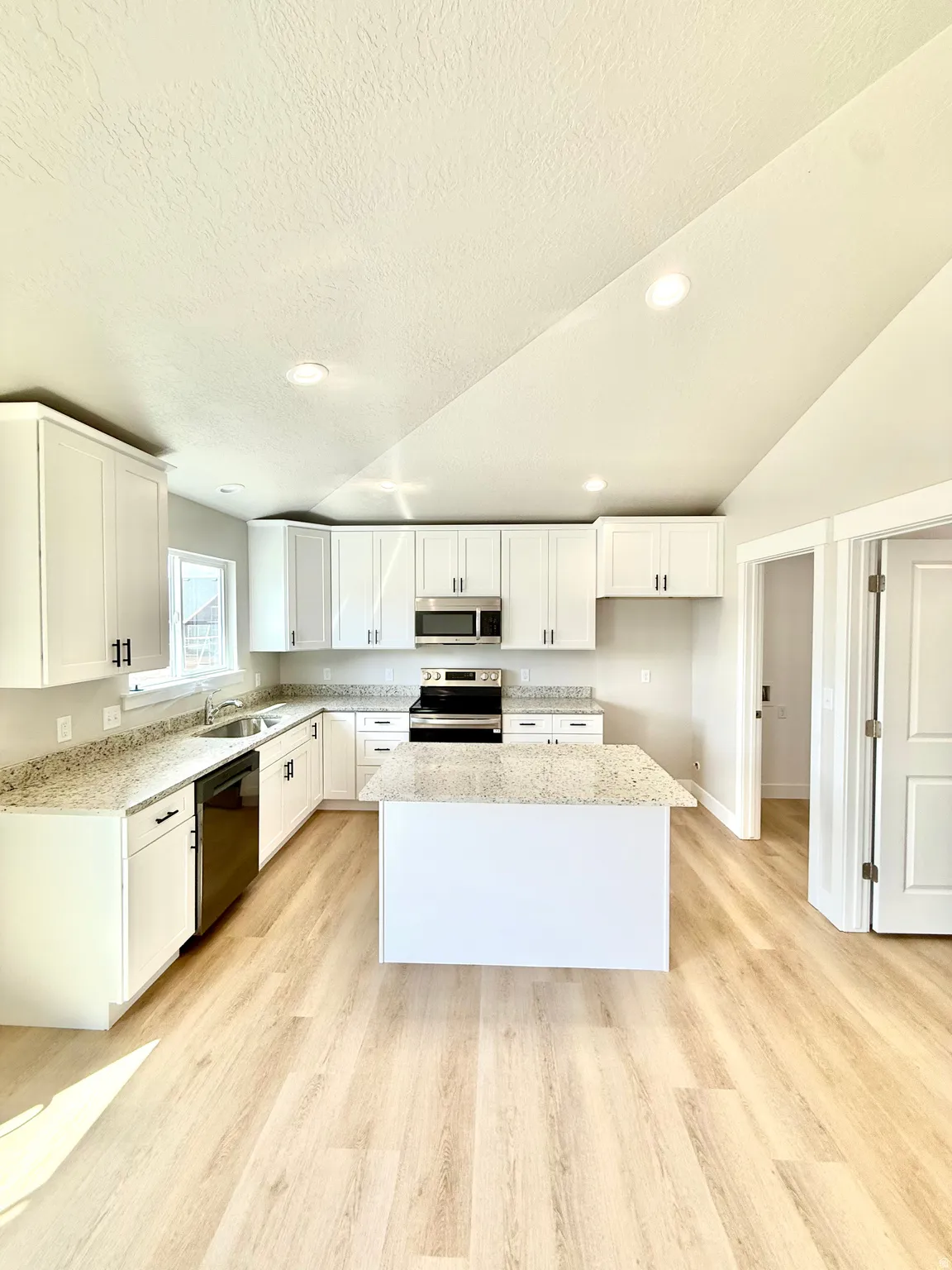 Kitchen featuring stainless steel appliances, light wood-style flooring, white cabinetry, a center island, and recessed lighting
