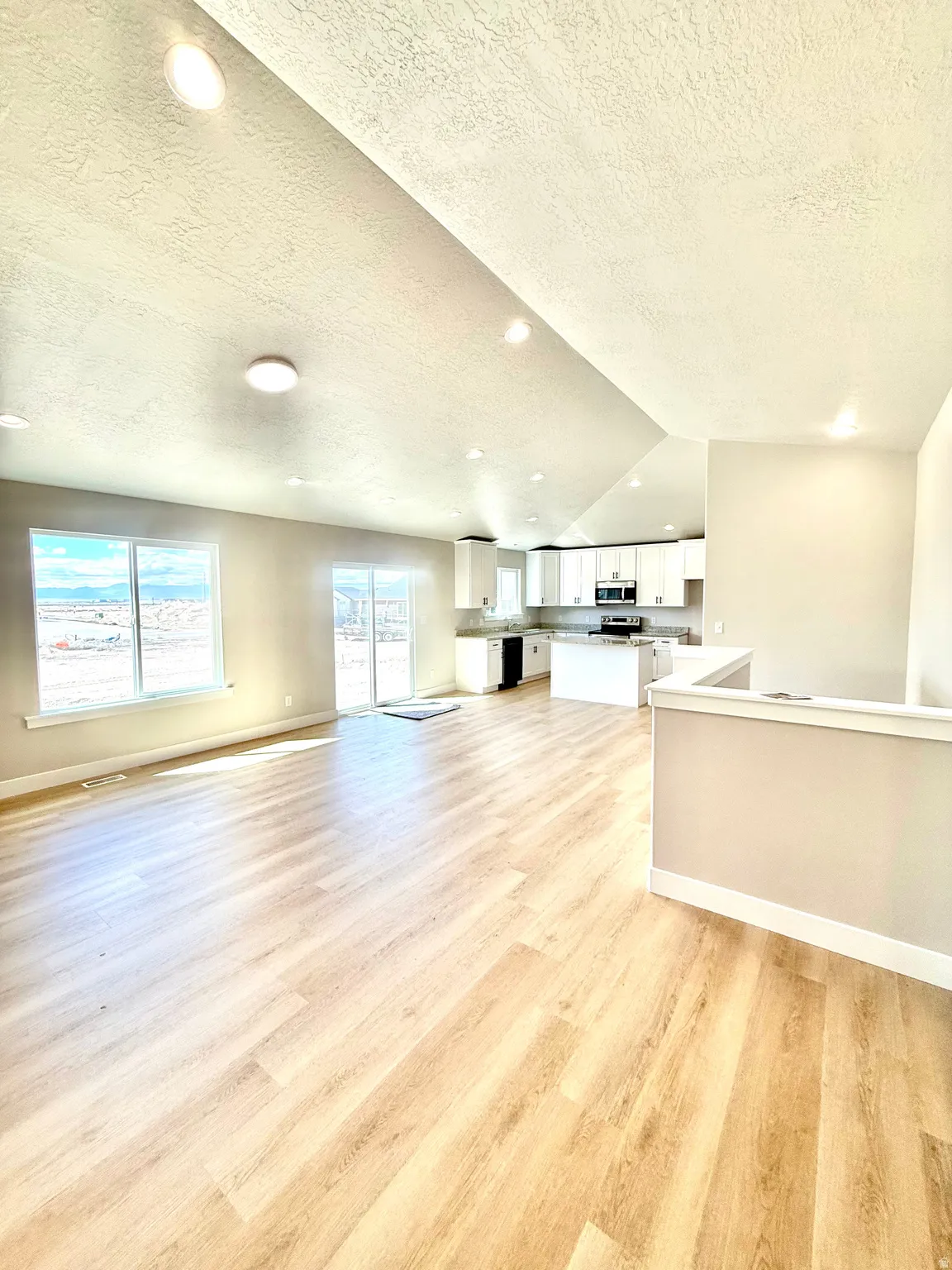 Unfurnished living room featuring a textured ceiling, light wood-type flooring, and recessed lighting