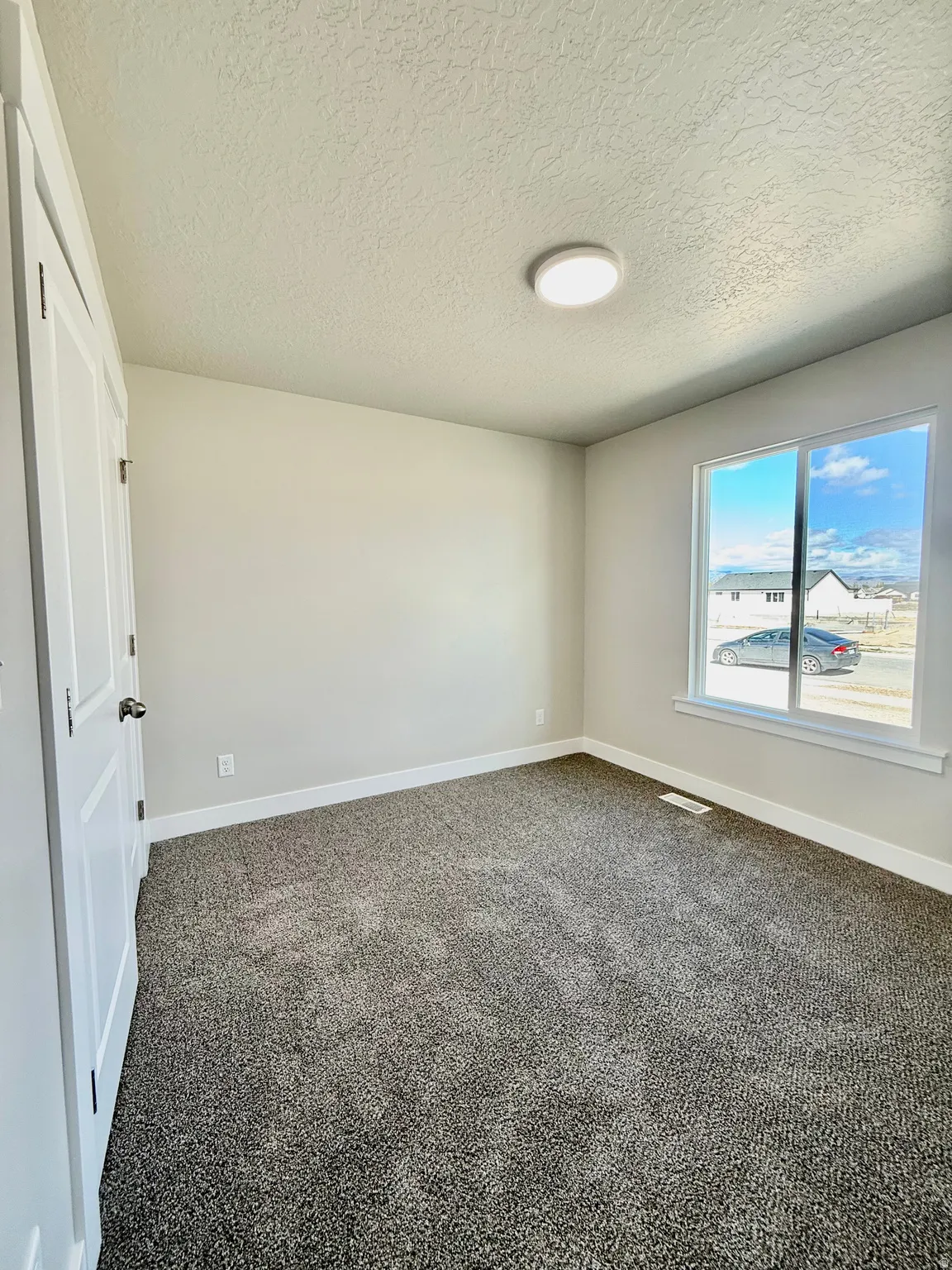 Unfurnished room with dark carpet and a textured ceiling