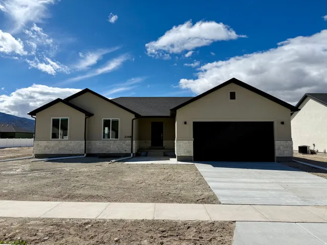 Ranch-style home featuring stone siding, driveway, and a garage