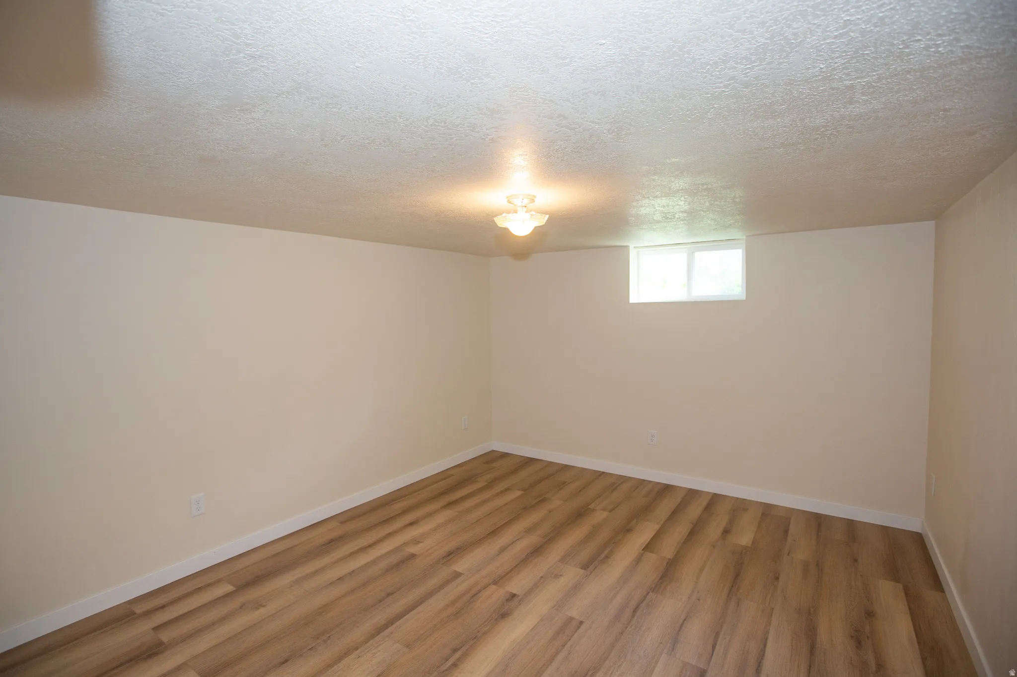 Remodeled bedroom with a textured ceiling and light LVP floors