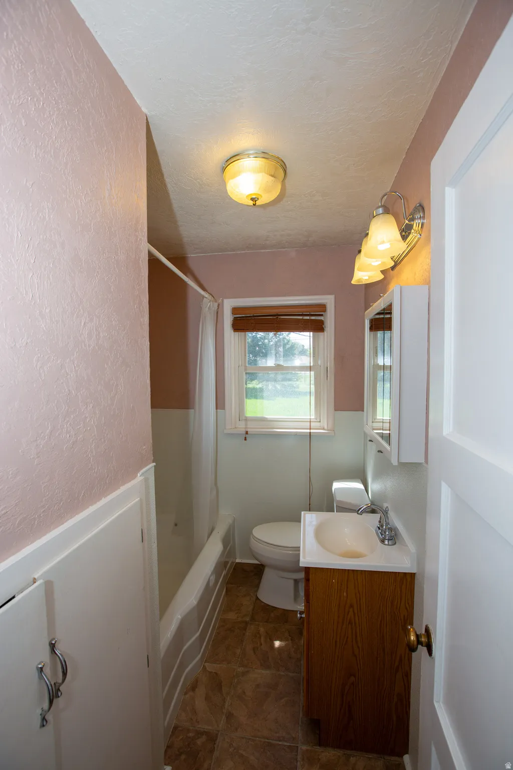 Full bath with a textured wall, vanity, a textured ceiling, and shower / bath combination with curtain