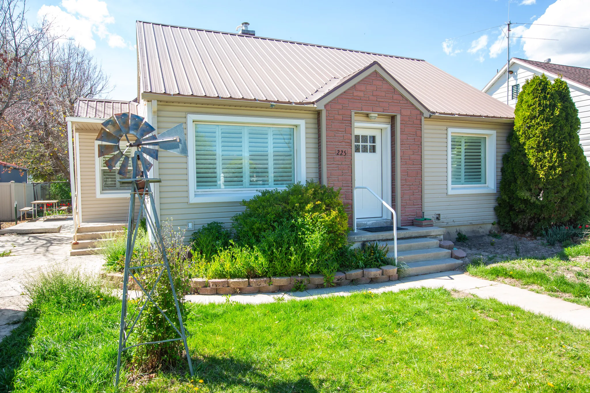 Bungalow featuring brick siding, a front lawn, and a metal roof