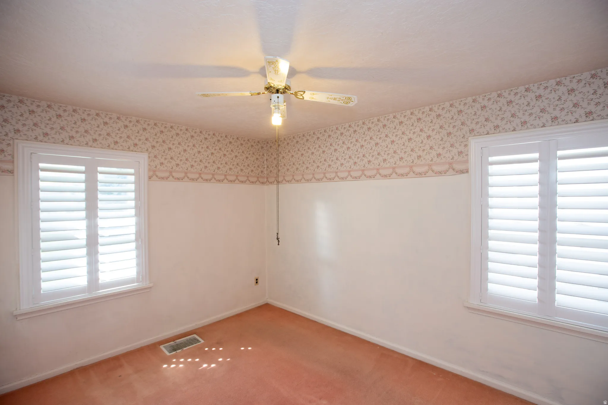 Carpeted bedroom with a textured ceiling,ceiling fan and plantation shutters