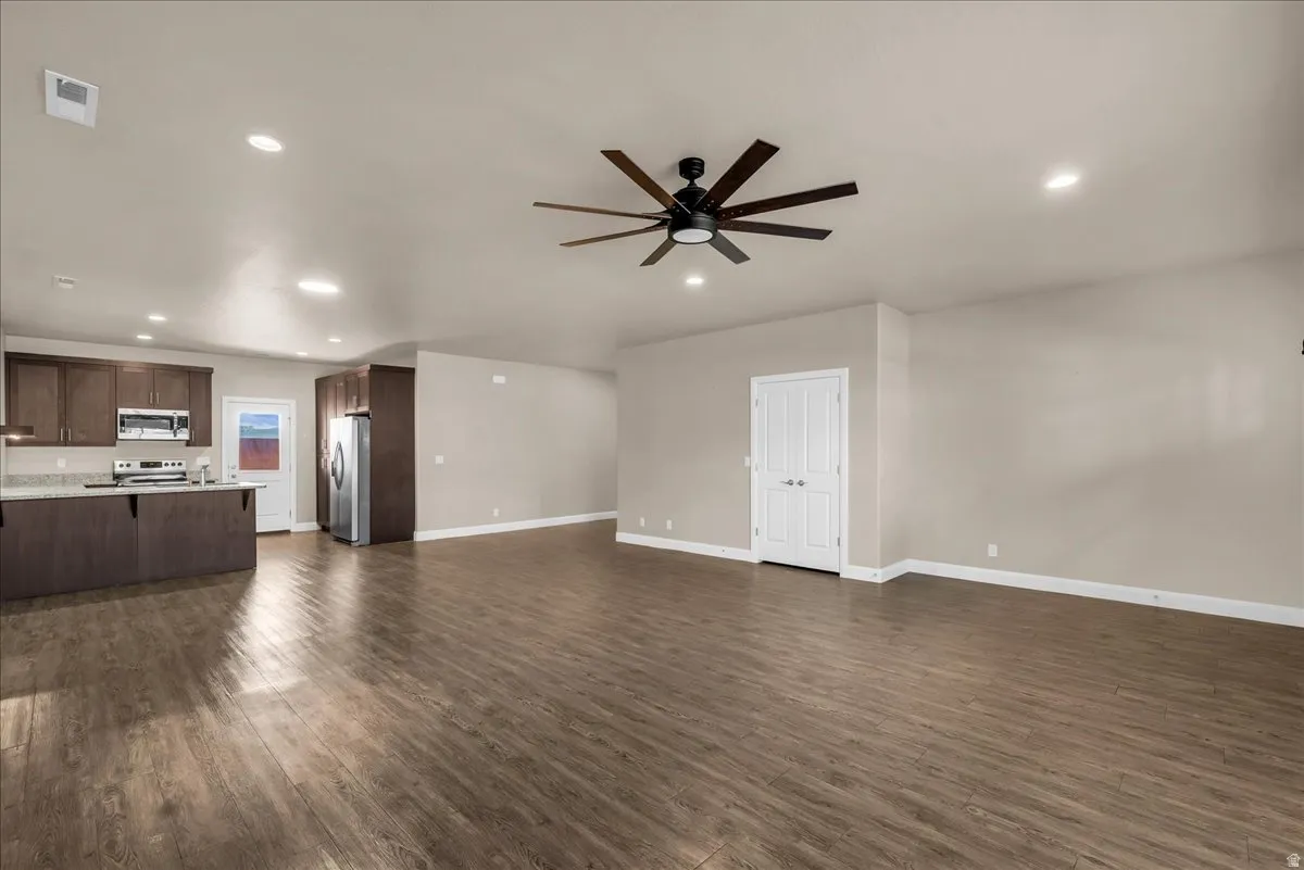 Unfurnished living room featuring dark wood-style floors, recessed lighting, and a ceiling fan