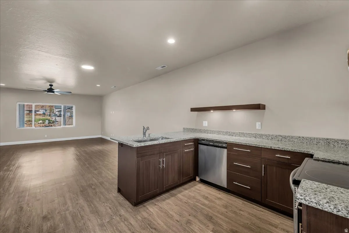 Kitchen featuring a peninsula, dark wood finish cabinetry, electric range, light stone countertops, and recessed lighting