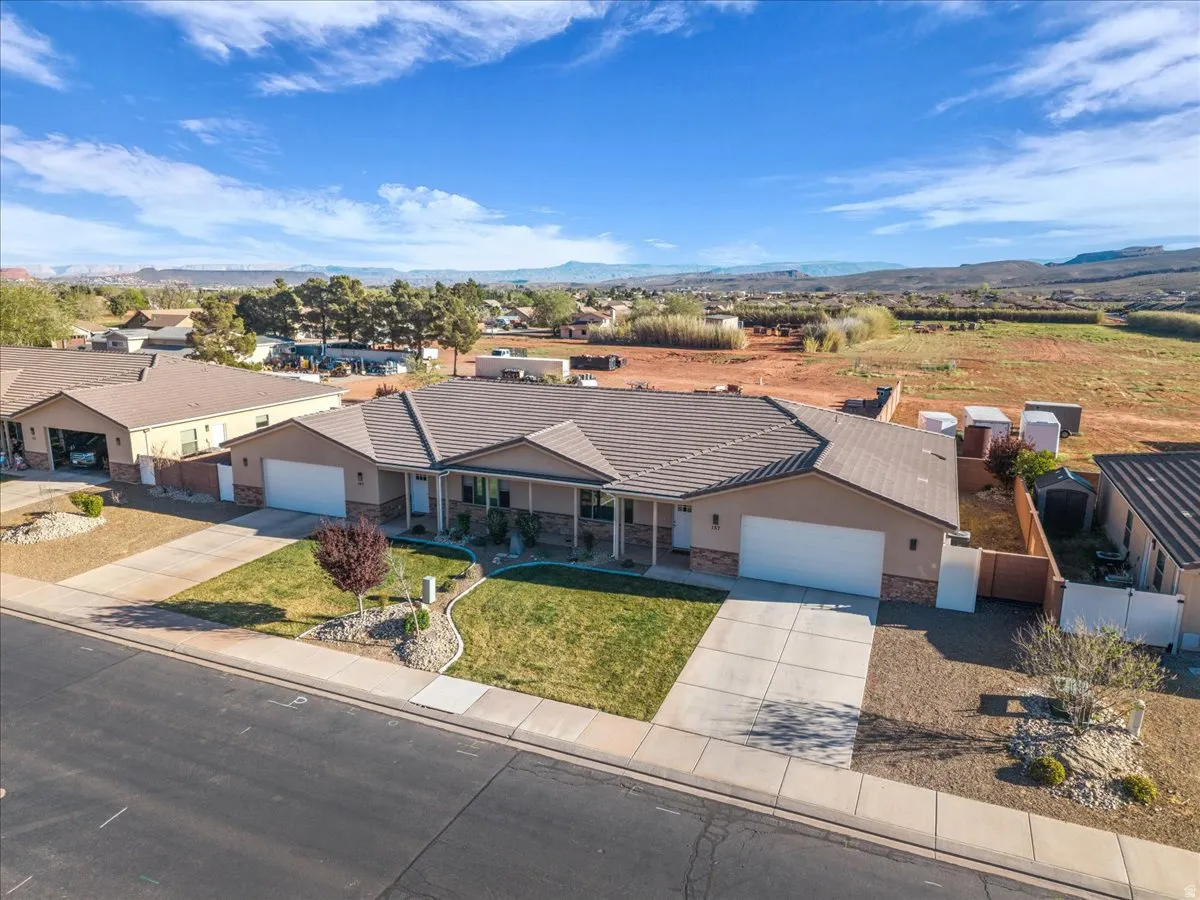 View of front of property featuring driveway, an attached garage, stone siding, stucco siding, and a mountain view