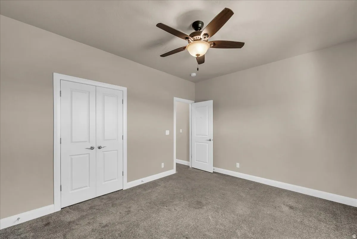 Unfurnished bedroom featuring carpet floors, a ceiling fan, and a closet