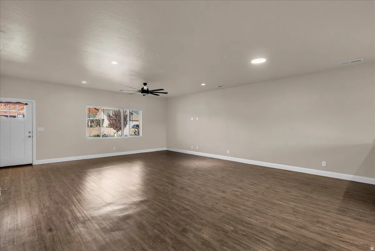 Unfurnished living room featuring dark wood-style floors, recessed lighting, and ceiling fan
