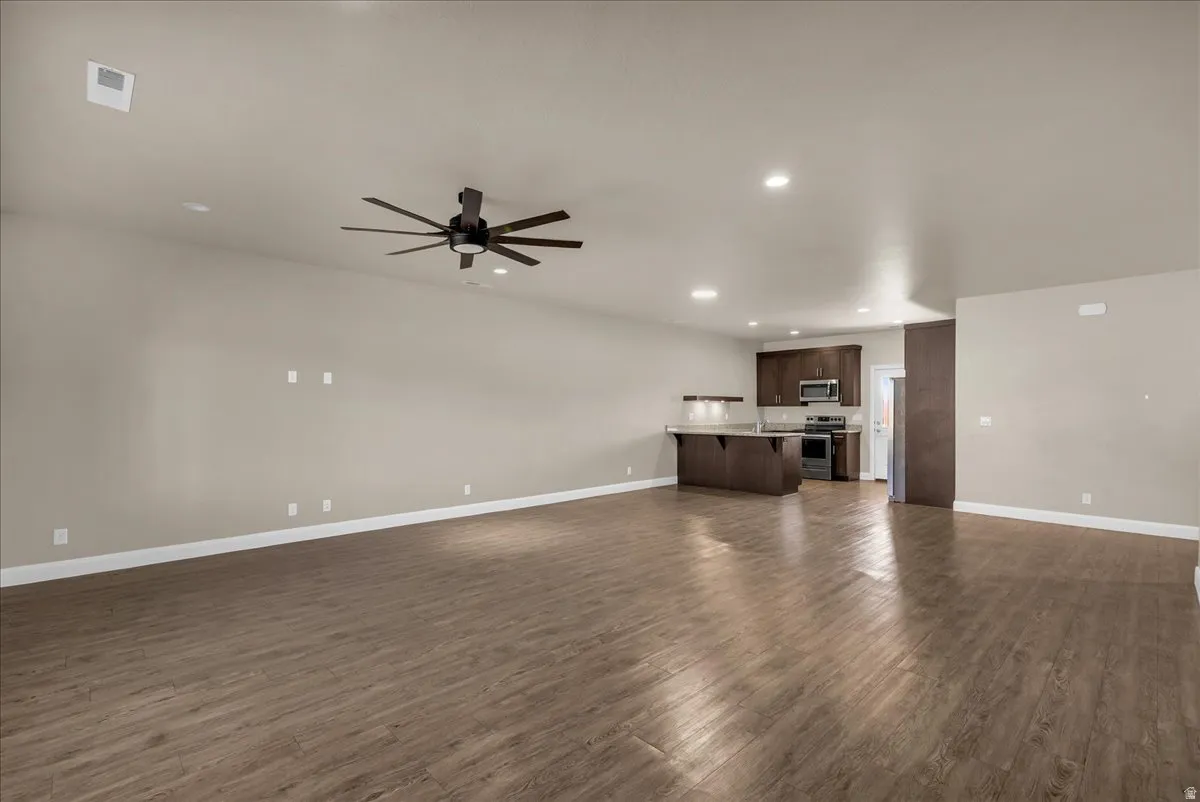 Unfurnished living room with a ceiling fan, dark wood-type flooring, and recessed lighting