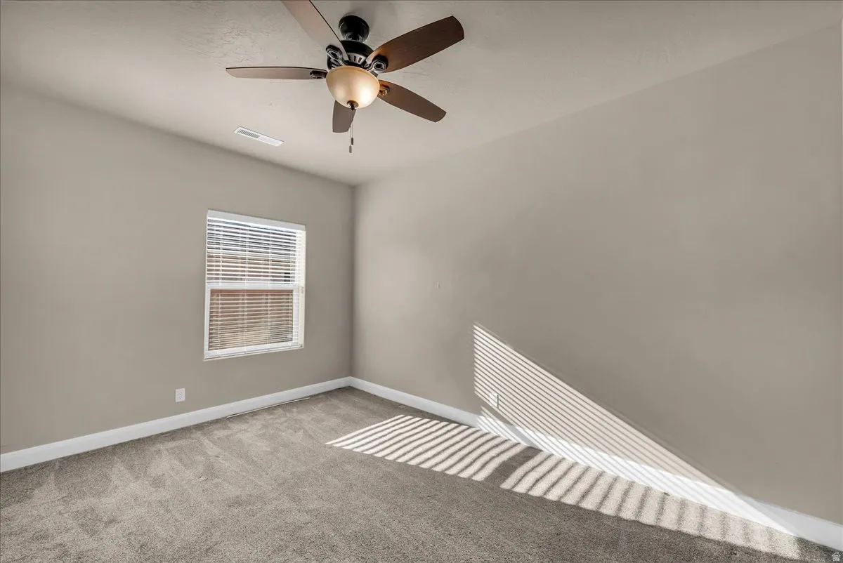 Unfurnished room featuring ceiling fan and light carpet