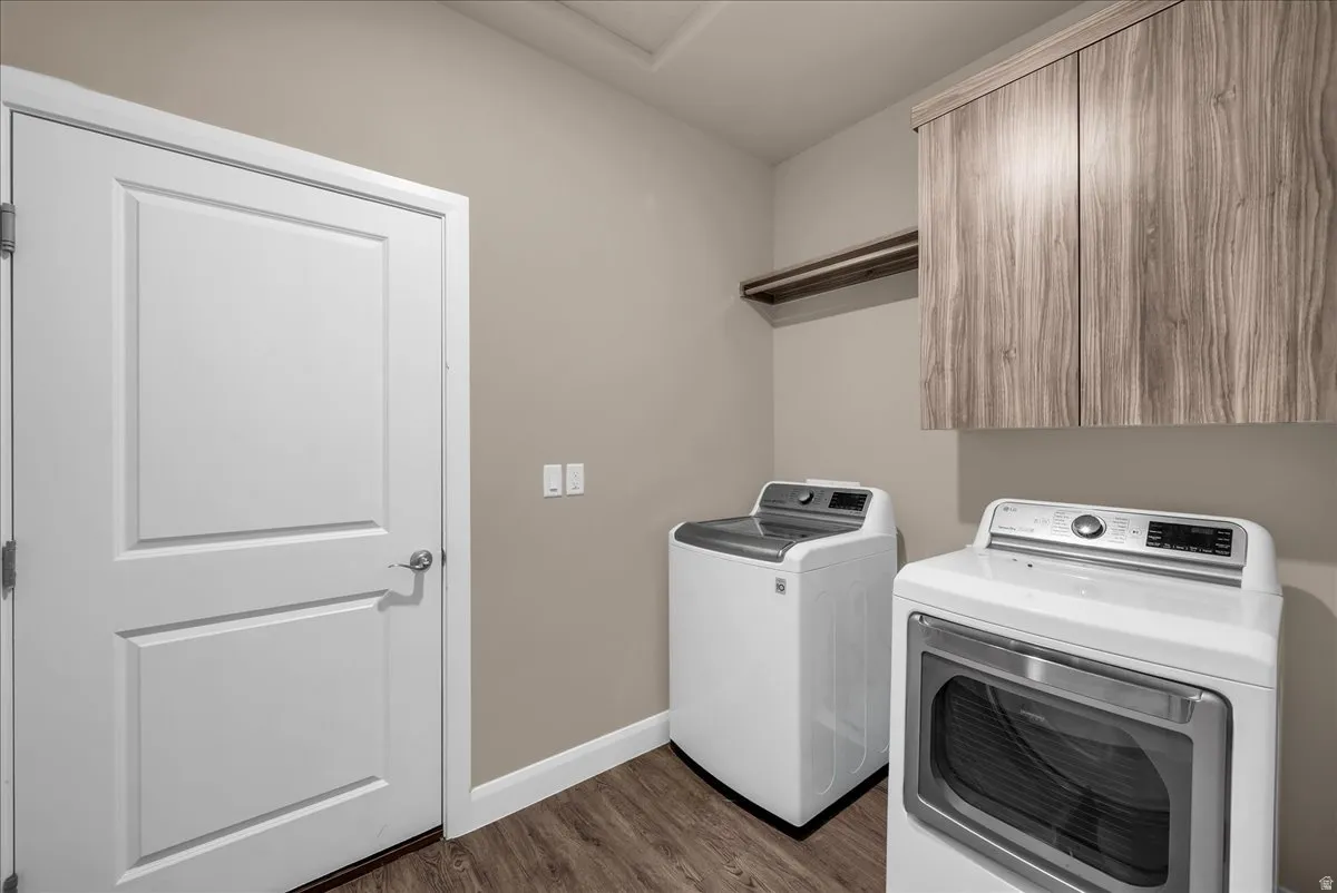 Laundry room with washing machine and clothes dryer, dark wood-type flooring, and cabinet space