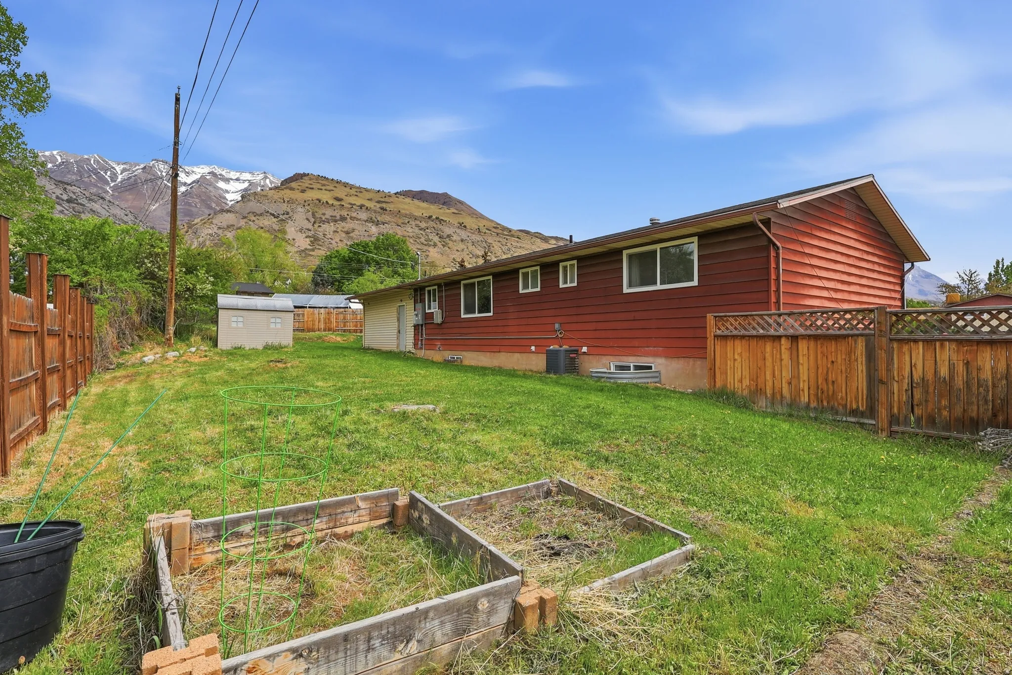 Fenced backyard with a mountain view, a storage shed, and a garden
