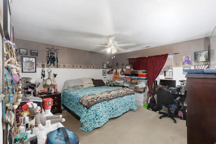 Bedroom featuring an office area, light colored carpet, and a ceiling fan