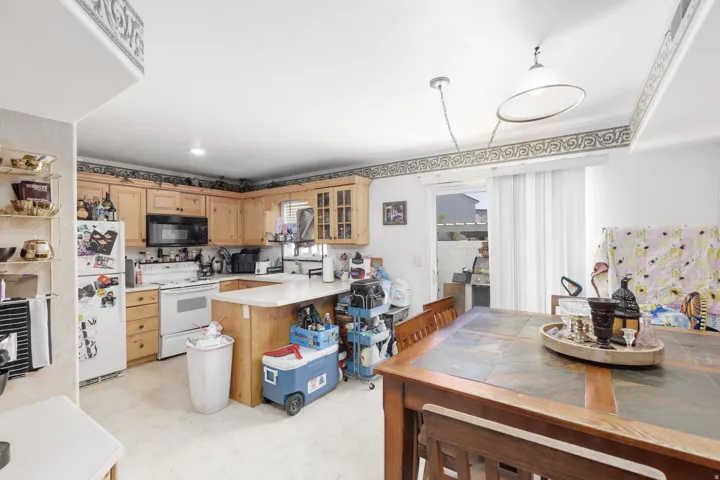 Kitchen with light flooring, light countertops, white appliances, a peninsula, and glass insert cabinets