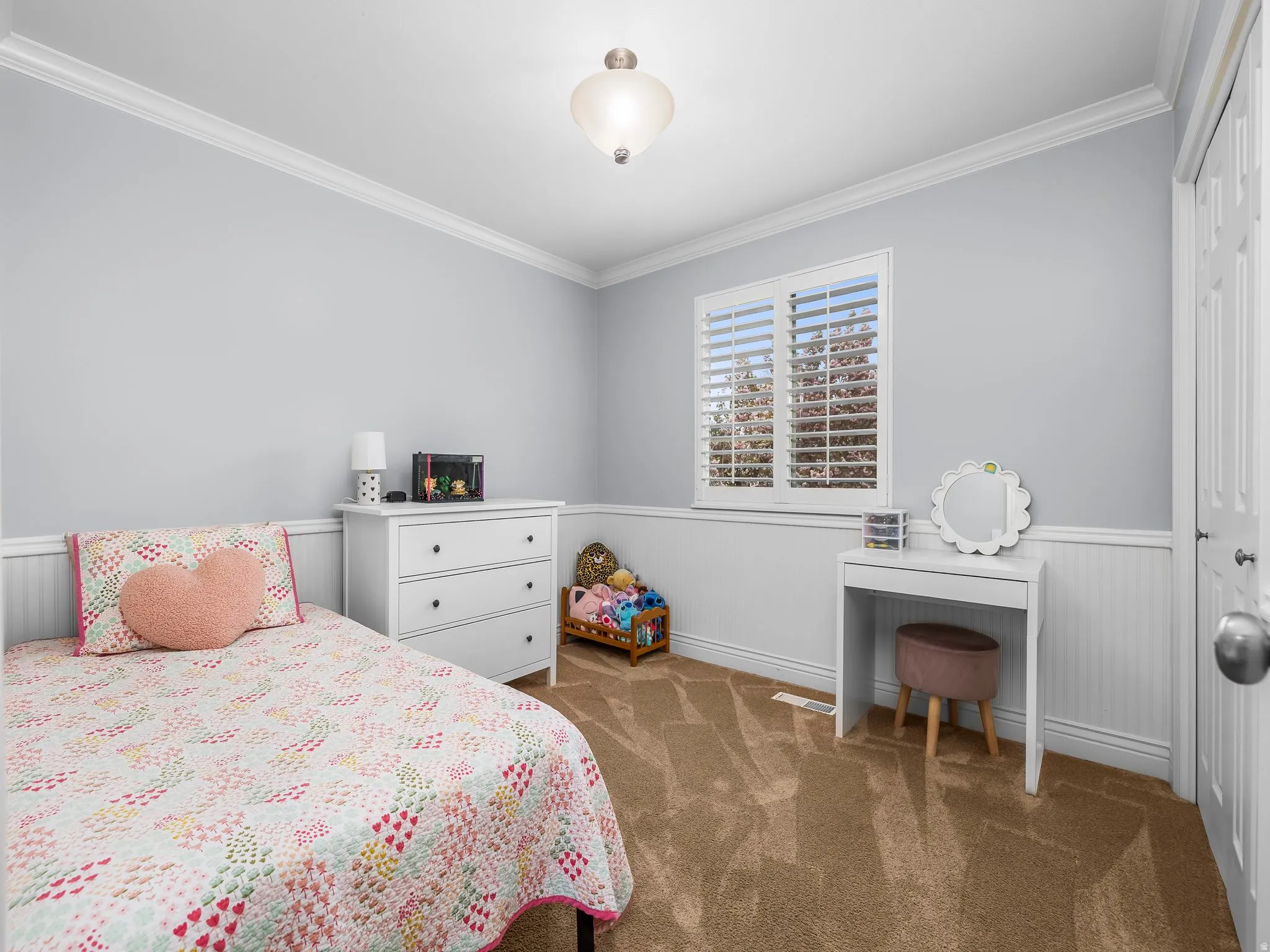 Bedroom featuring wainscoting, crown molding, dark carpet, and a closet