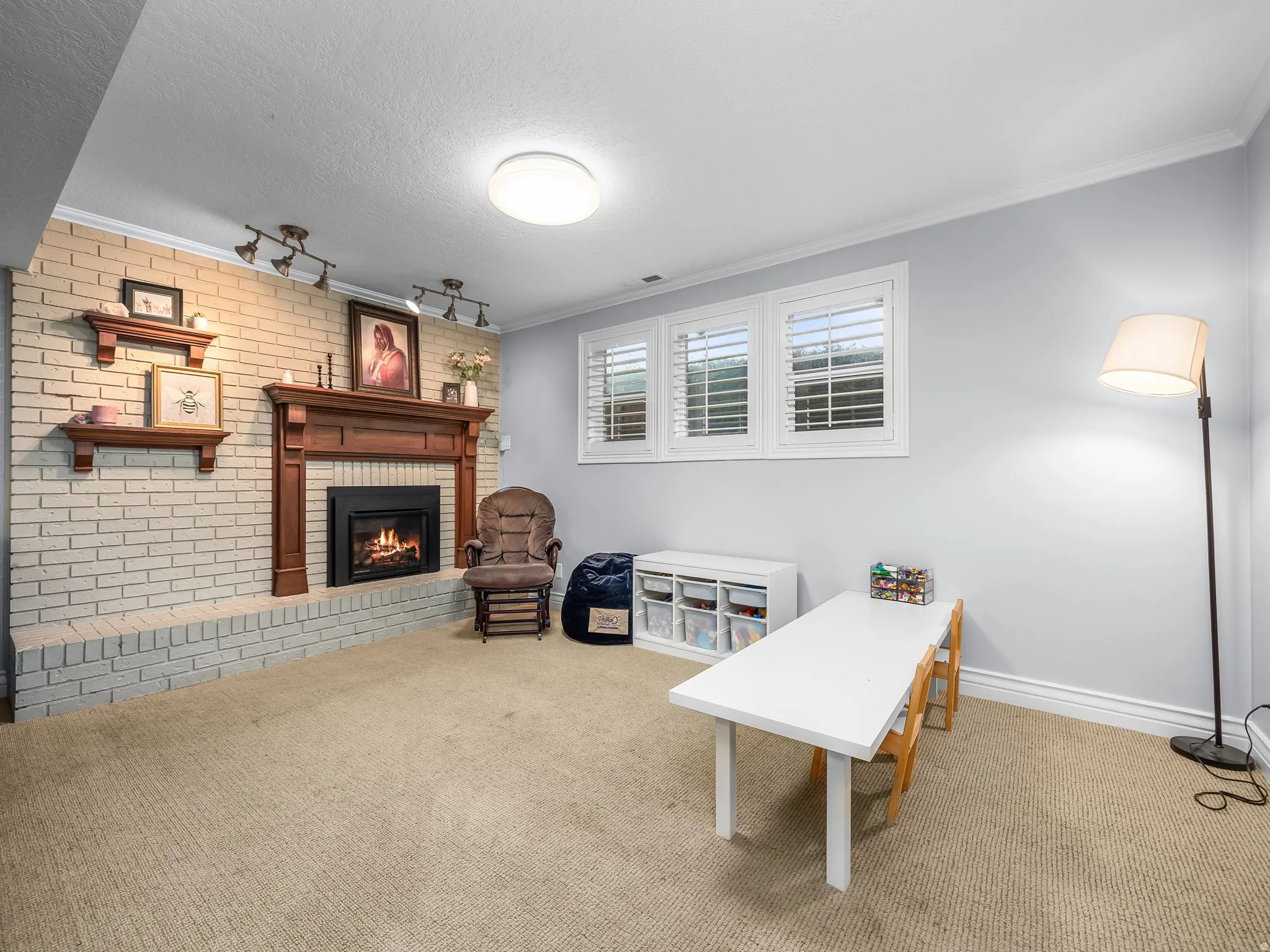 Living Area featuring brick wall, carpet flooring, ornamental molding, and a brick fireplace