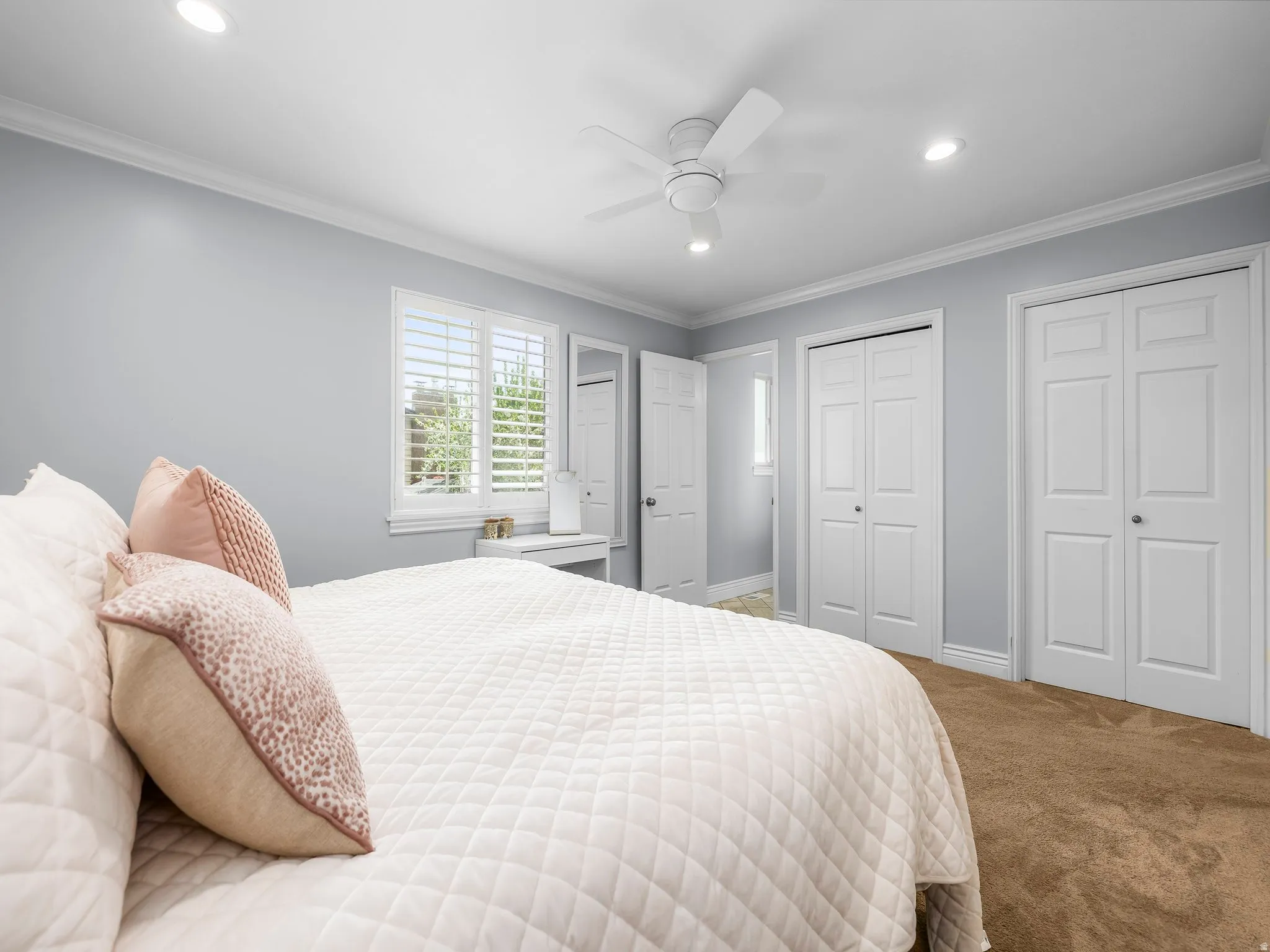 Carpeted bedroom with two closets, crown molding, recessed lighting, and ceiling fan