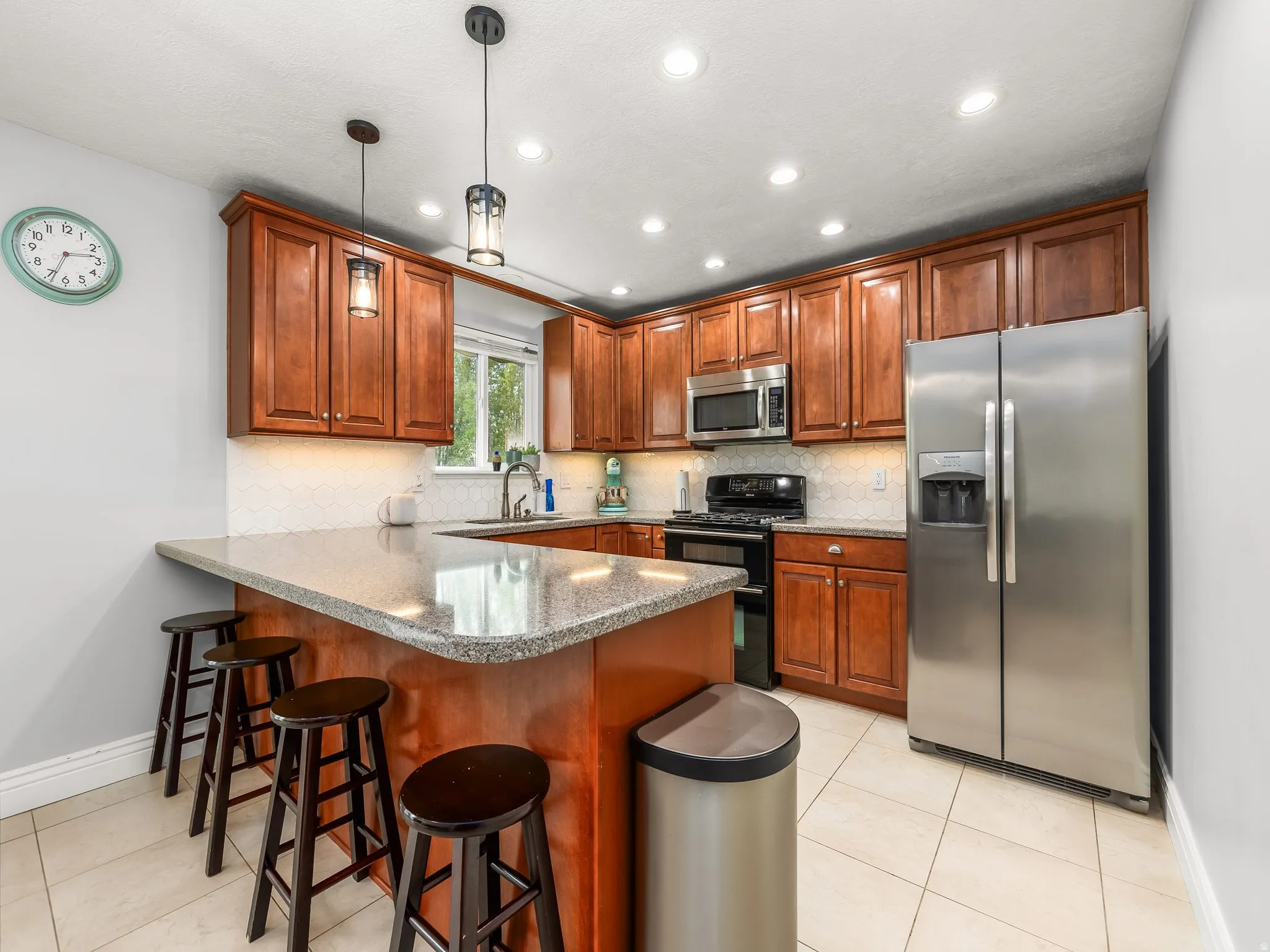 Kitchen featuring a breakfast bar area, stainless steel appliances, a peninsula, tasteful backsplash, and wood finish cabinets