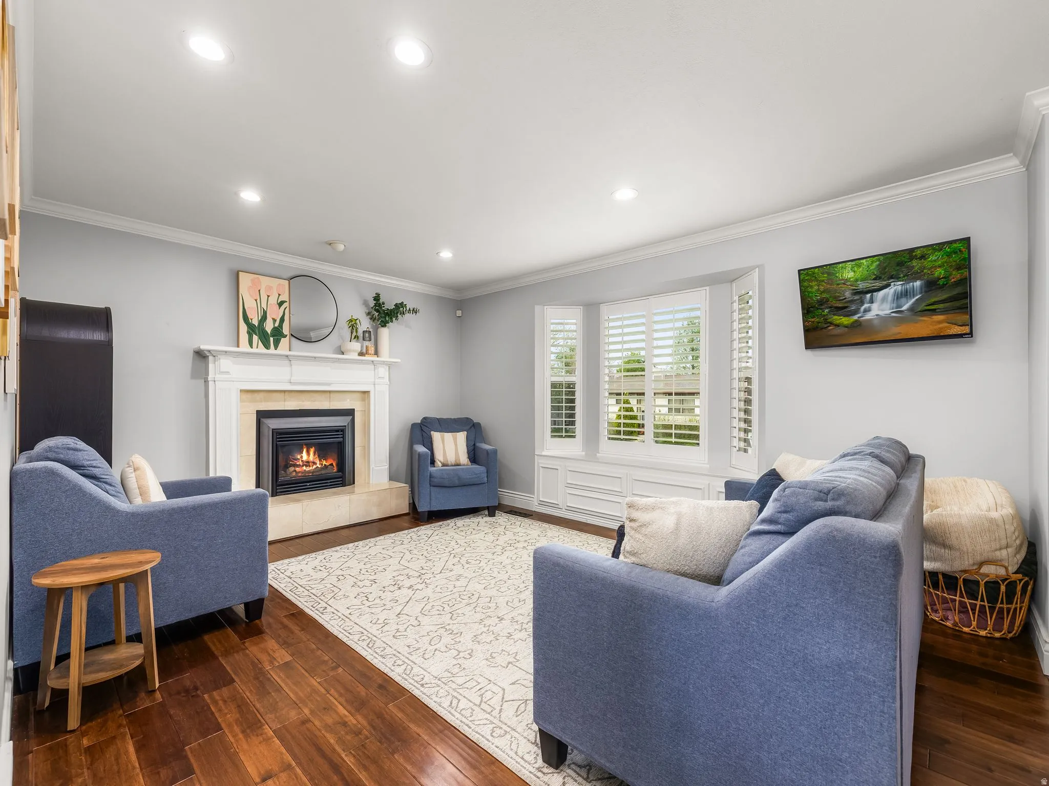 Living area featuring ornamental molding, dark wood-style floors, recessed lighting, and a fireplace